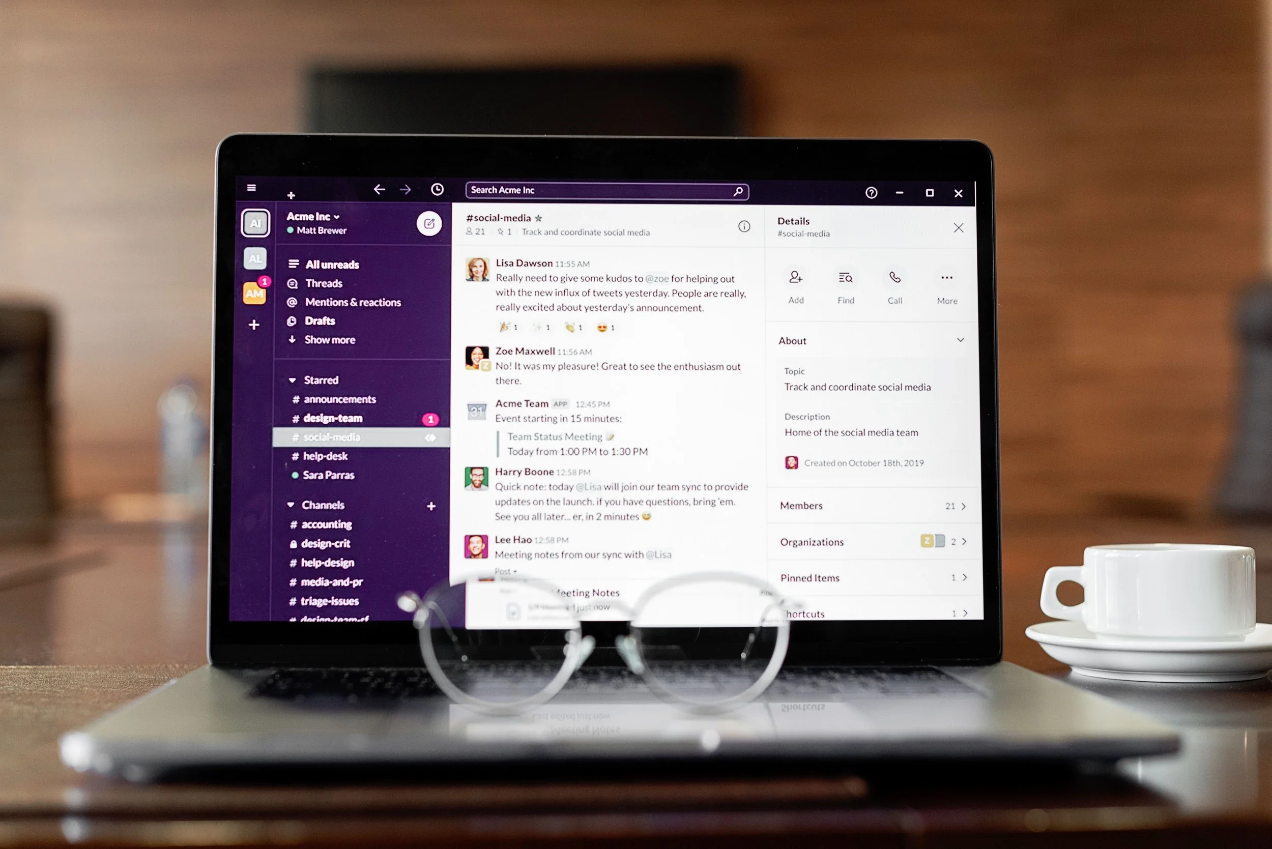 laptop screen with business chat communications platform on screen with a coffee cup next to computer on desk and glasses sitting on keyboard