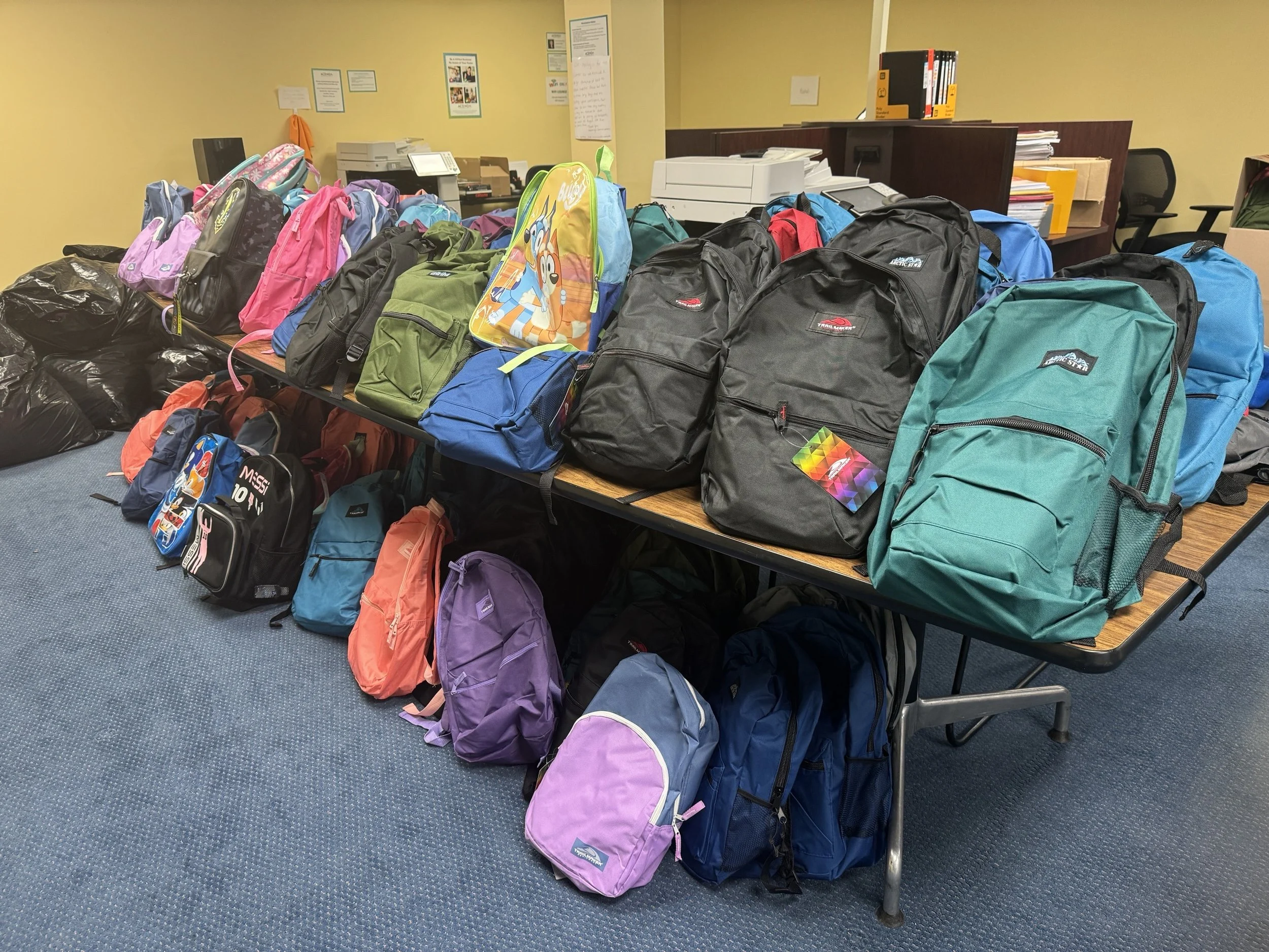 backpack and school supply donations on tables for Acenda's clients