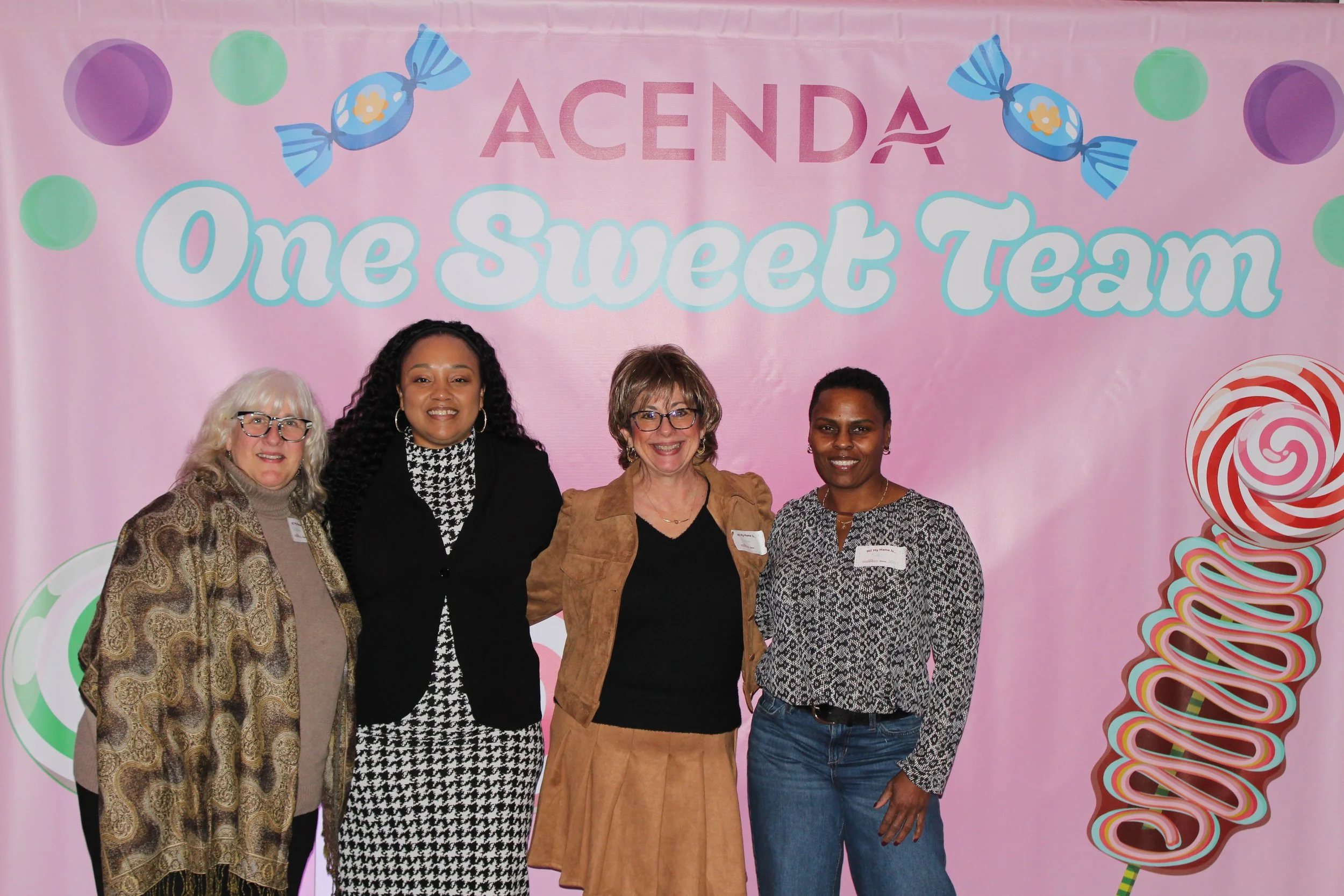 Four Acenda employees pose in front of a "One Sweet Team" backdrop for Staff Bash 2026
