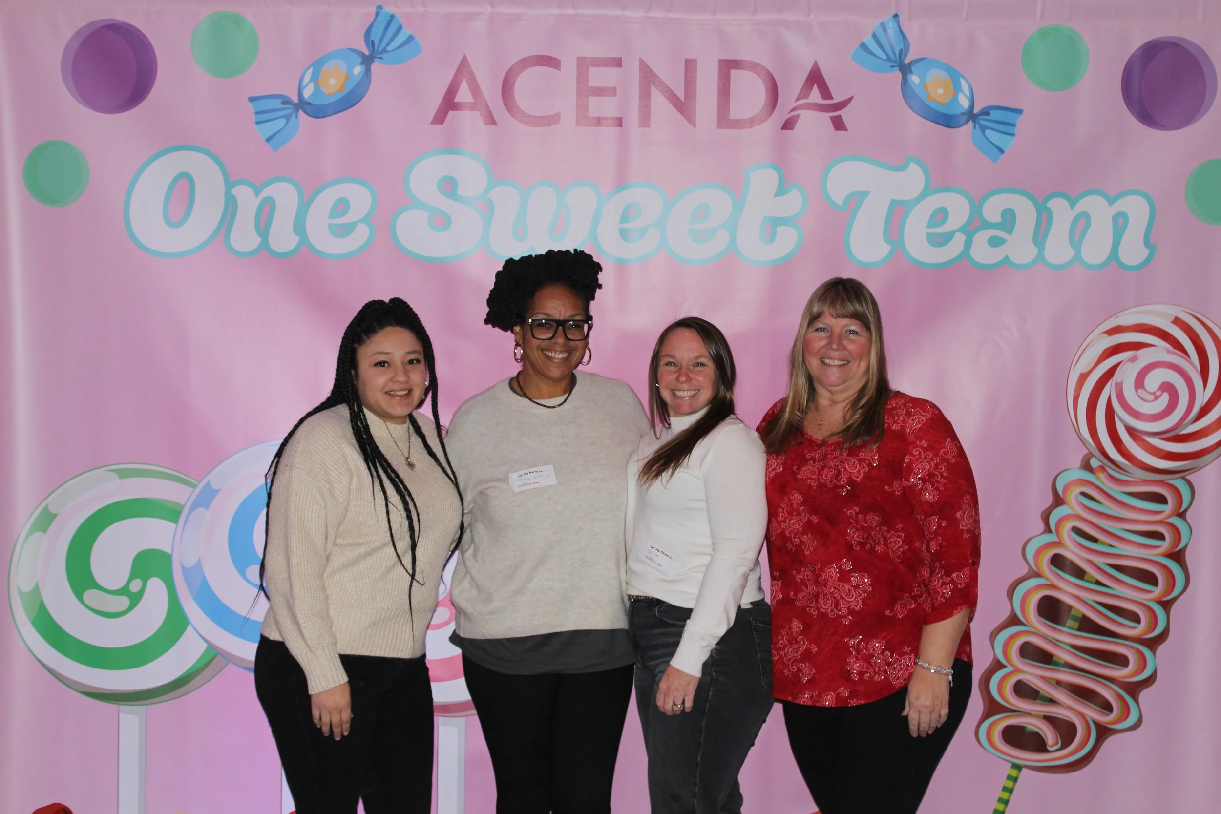 Four Acenda employees pose in front of a "One Sweet Team" backdrop for Staff Bash 2026