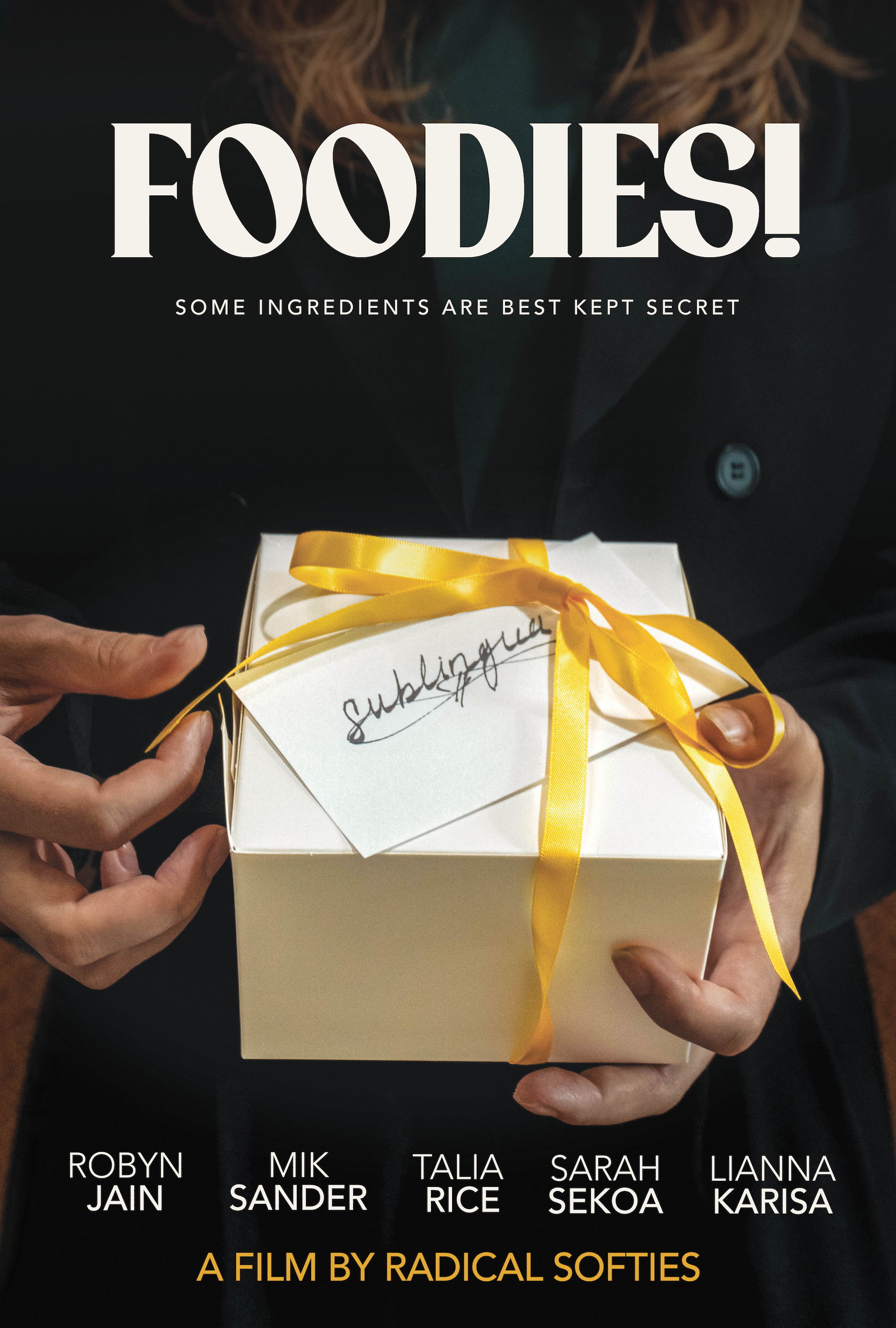 A woman holding a white gift box wrapped with a yellow ribbon. The gift box has a tag that says 'submitting.' The background contains a poster with the title 'FOODIES!' and the tagline 'Some ingredients are best kept secret.' The poster lists several names, including Robyn Jain, Mik Sander, Talia Rice, Sarah Sekoia, and Lianna Karisa, and mentions that it is a film by Radical Softies.