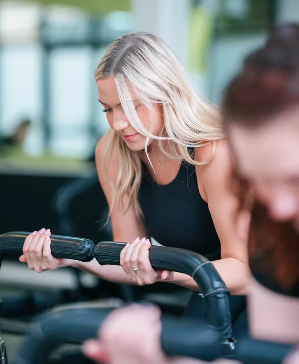 A blonde woman exercising at the gym on a rowing machine
