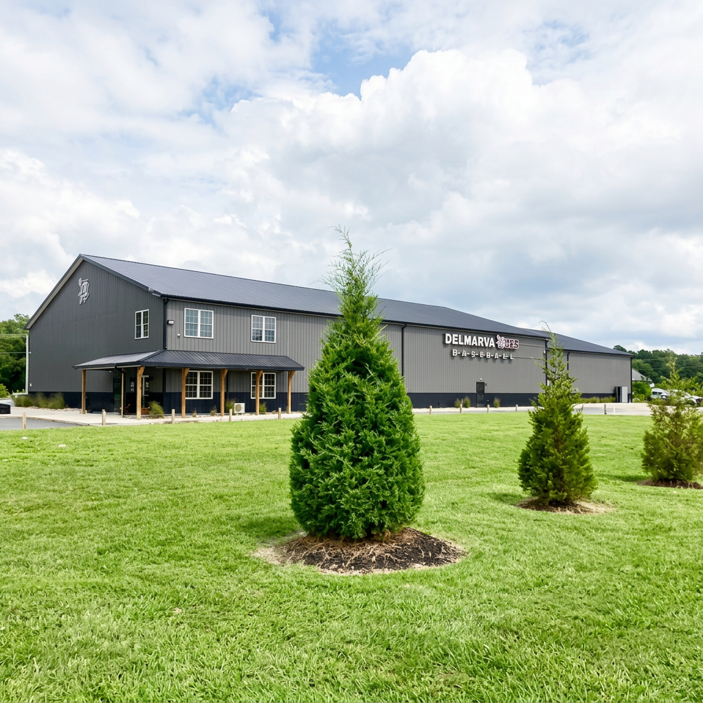 A large gray building with a sign that reads 'Delmarva' in a grassy area with small trees and a partly cloudy sky.