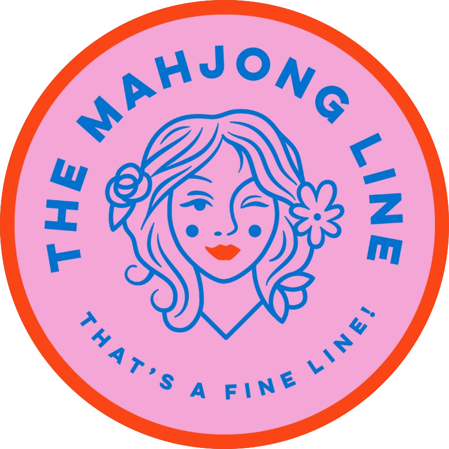 A circular logo with a pink background and orange border, featuring a stylized outline of a girl with wavy hair, a flower in her hair, and winking. The text around the girl reads "THE MAHONG LINE" and "THAT'S A FINE LINE!" in blue.