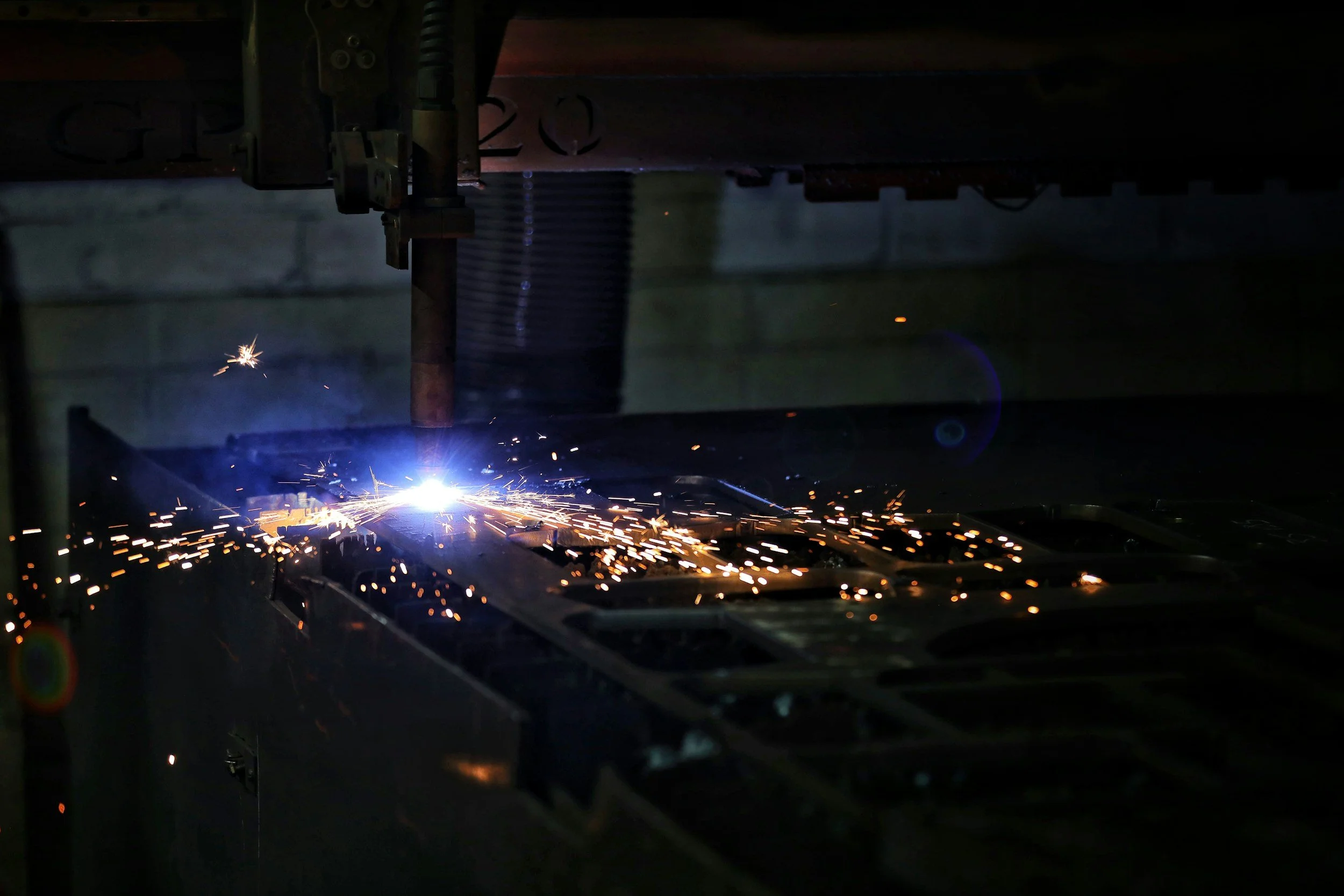 A welding process creating sparks and a bright blue light, with visible welding equipment and metal materials, likely in an industrial or workshop setting.