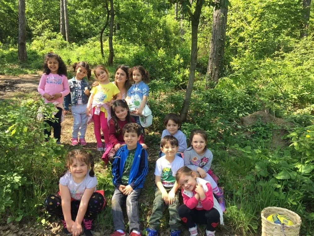 A group of young children, smiling and posing for a photo in a lush, green forest.
