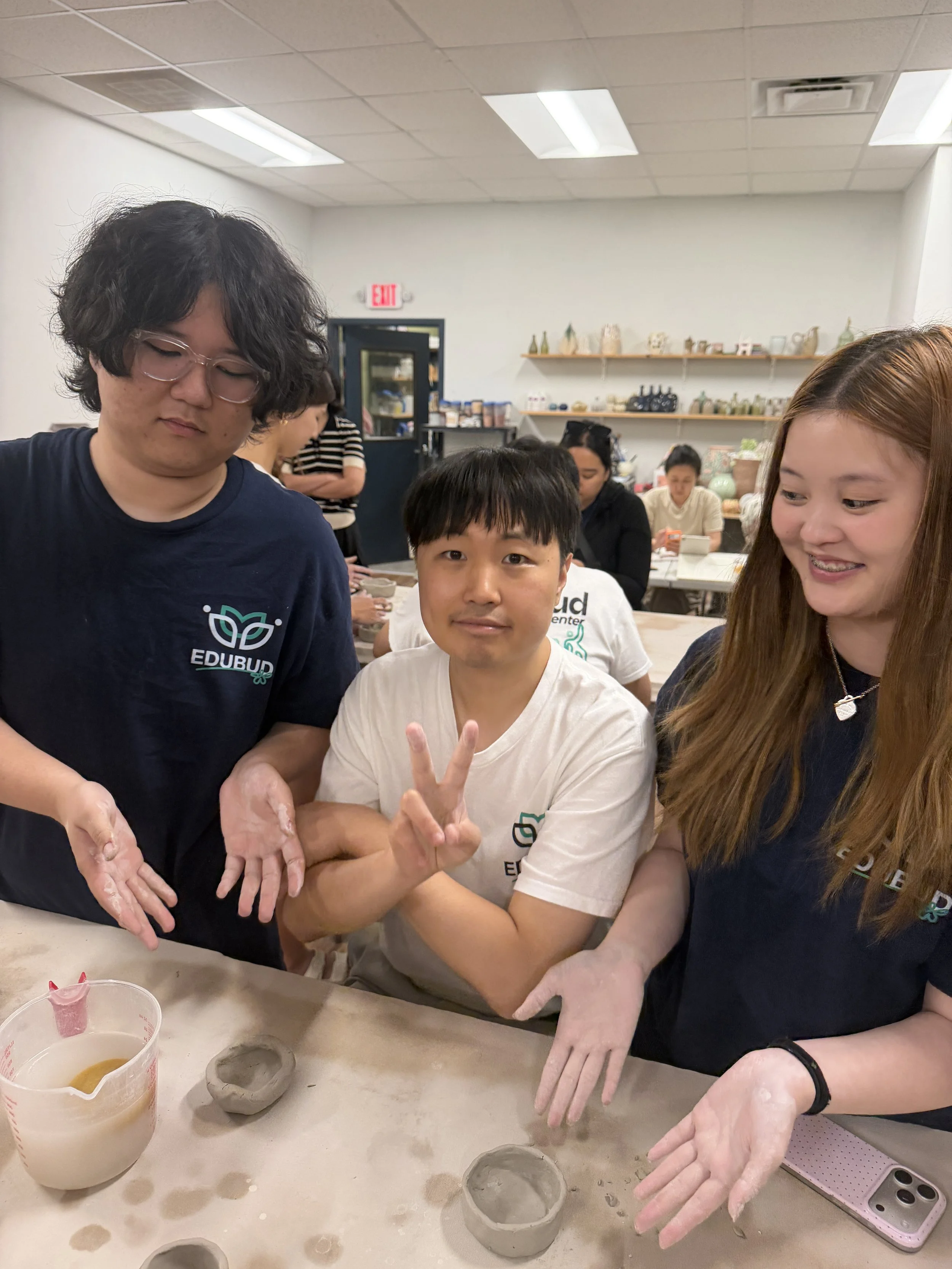 Group of people around a table in a workshop making pottery with clay and pottery molds.