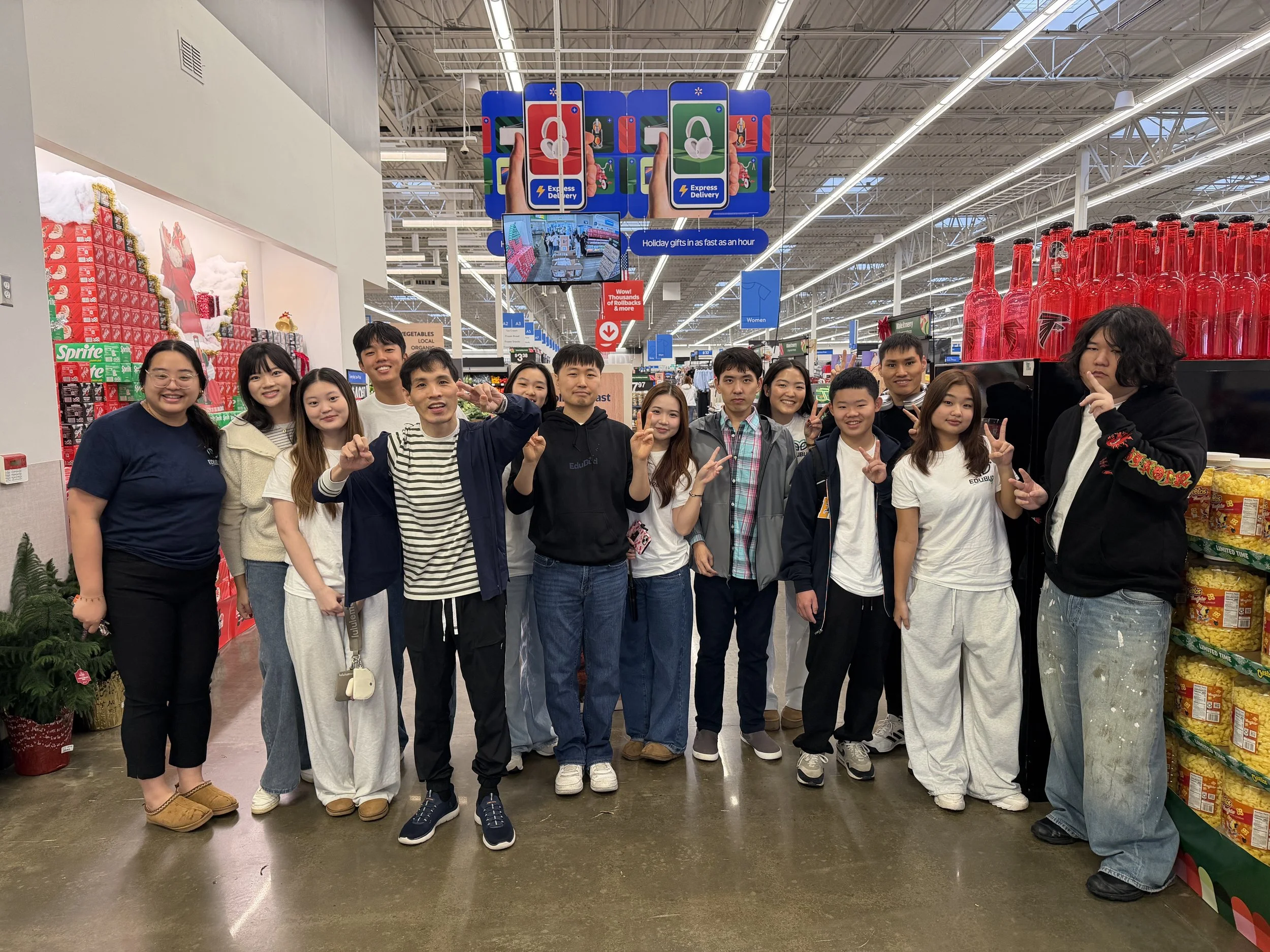 A group of people posing together inside a store, with holiday decorations and shelves stocked with products around them.