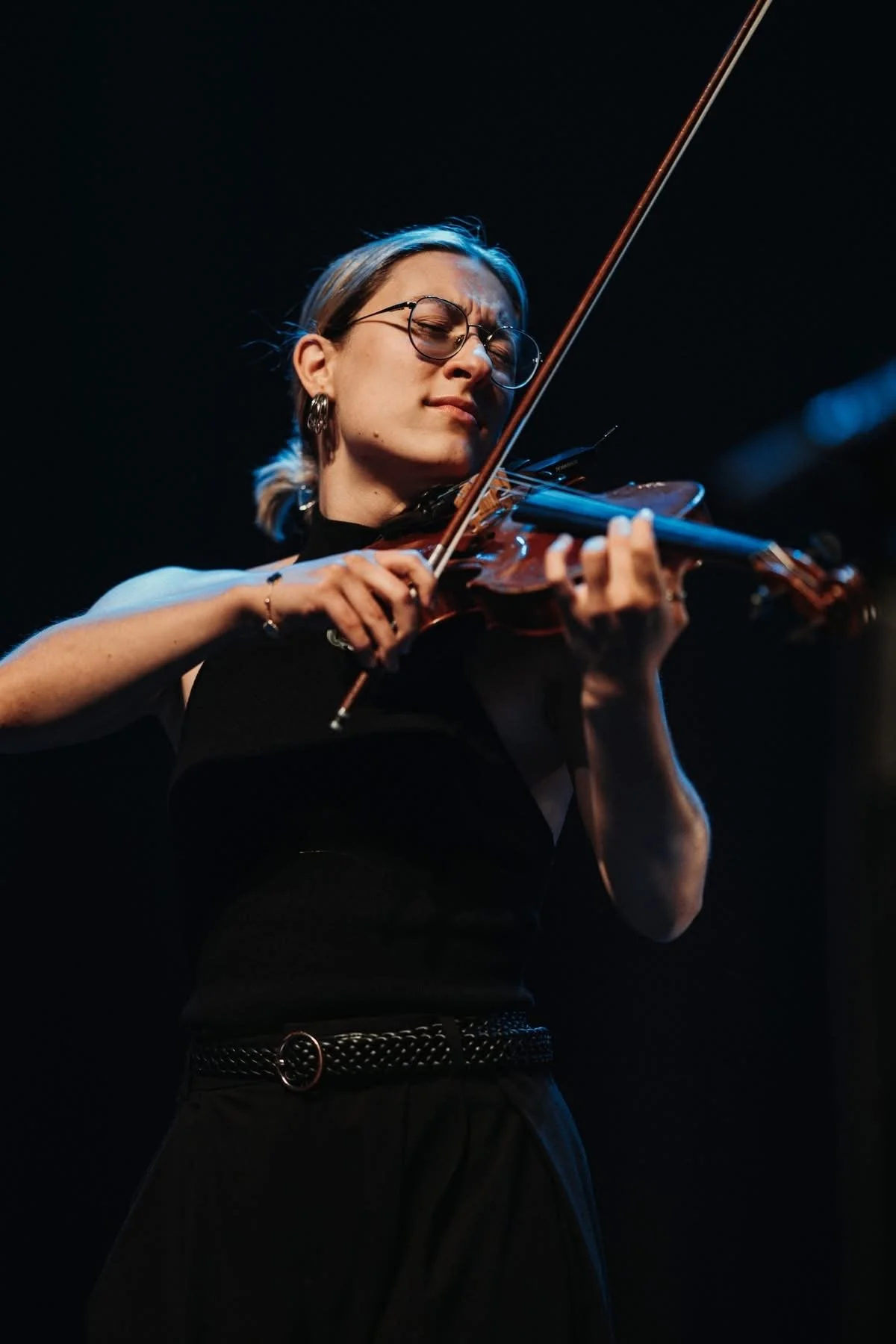Marianne Paquin jouant du violon sur scène, concentrée, derrière un fond noir.