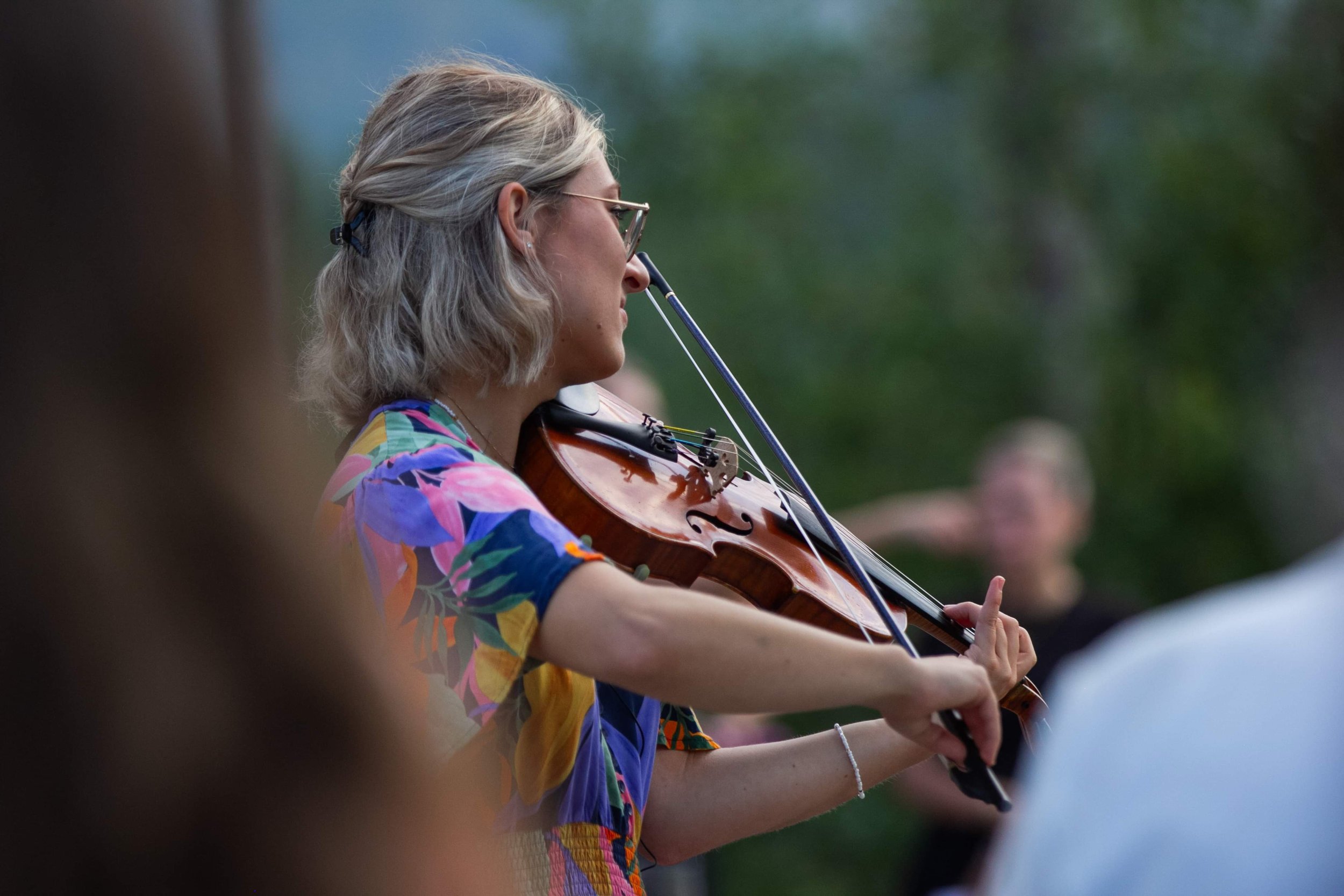 Marianne Paquin de profil jouant du violon lors d'un mariage, avec une robe colorée.