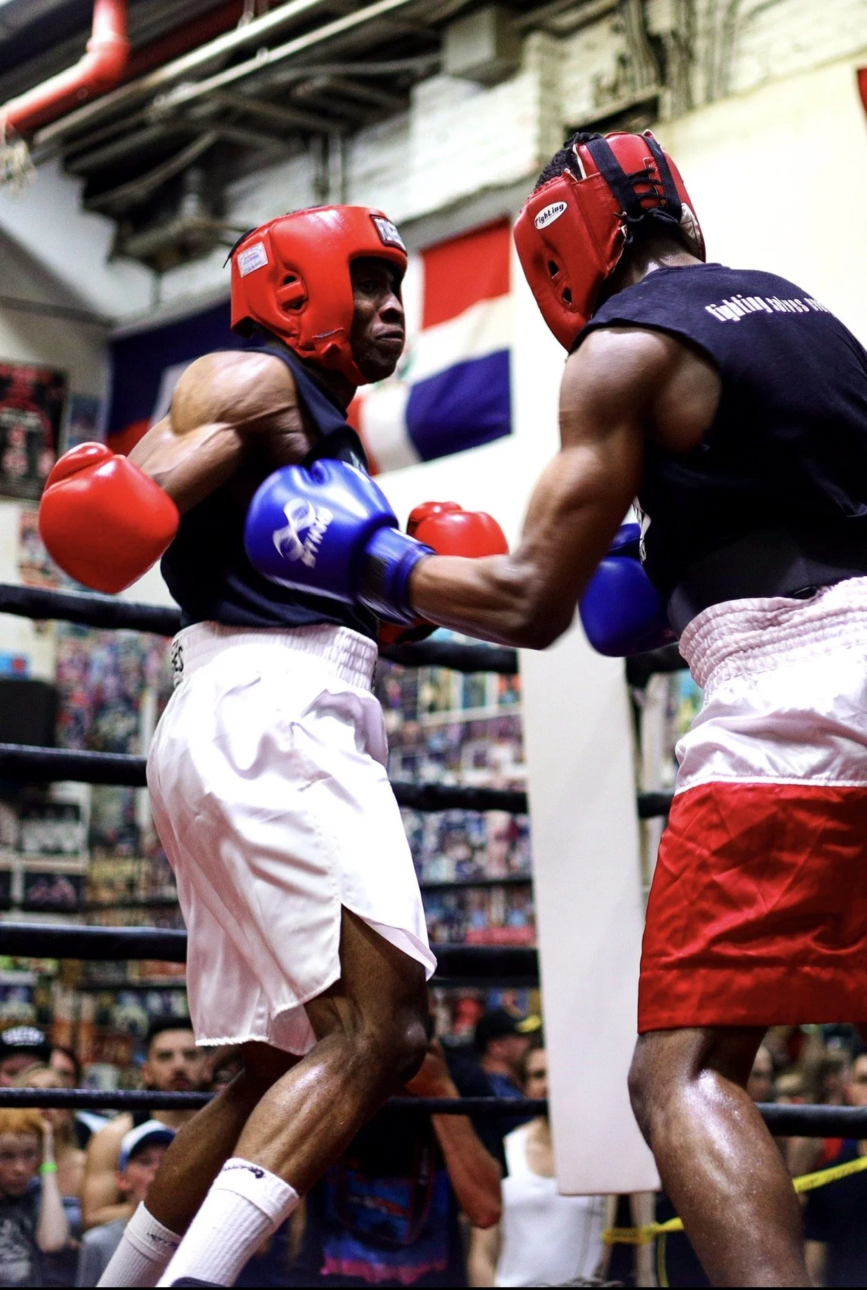 Two boxers wearing red headgear and gloves sparring in a boxing ring