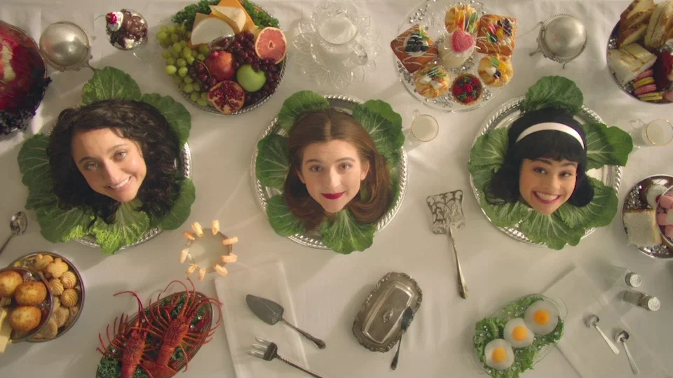 The three Debras' heads served on silver lettuce platters during a surreal banquet scene in Three Busy Debras.