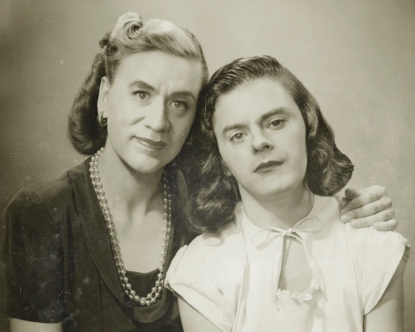 Fred Armisen and Bill Hader posing in 1940s women's attire and curled hair for a vintage black-and-white studio portrait.