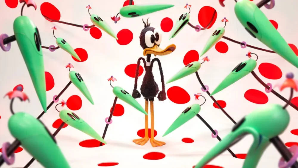 Daffy Duck standing amongst green alien stalks on a red polka-dot background.