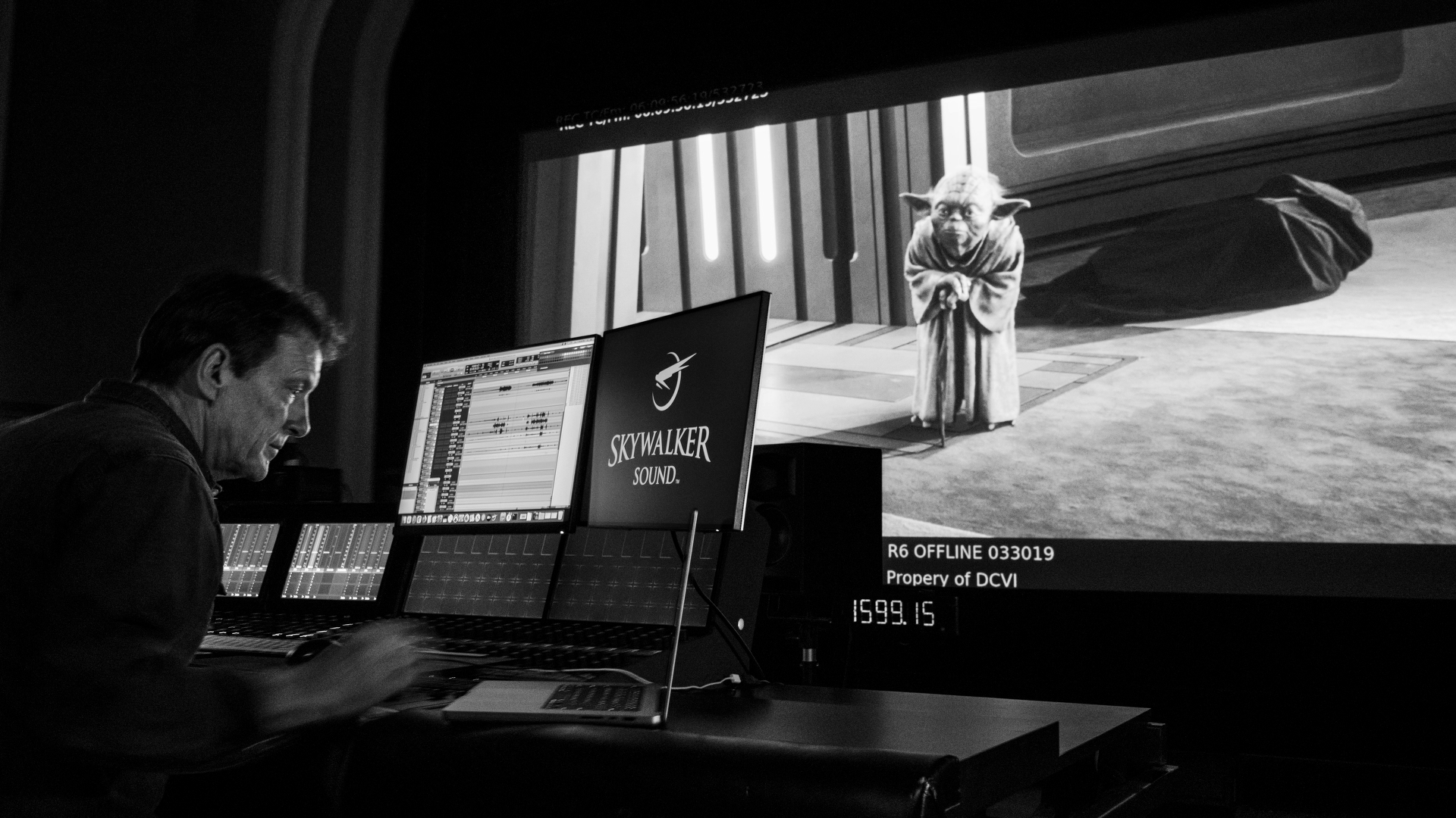 Sound editor at a Skywalker Sound audio console with Yoda displayed on a large screening monitor.