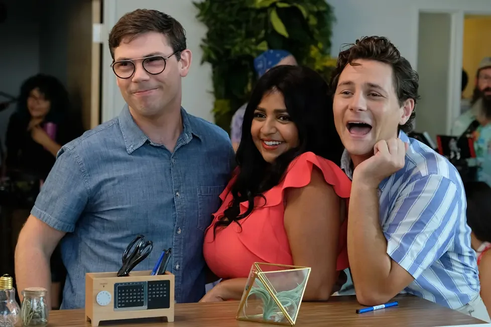 Ryan O'Connell, Punam Patel, and Augustus Prew smiling and posing together behind an office reception desk.