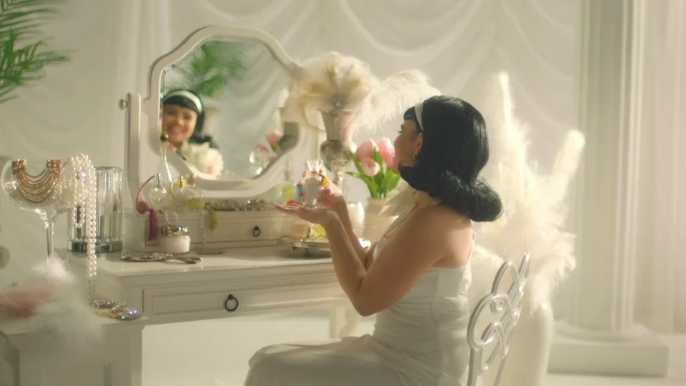 Woman in a retro white dress sitting at a vanity mirror in Three Busy Debras.