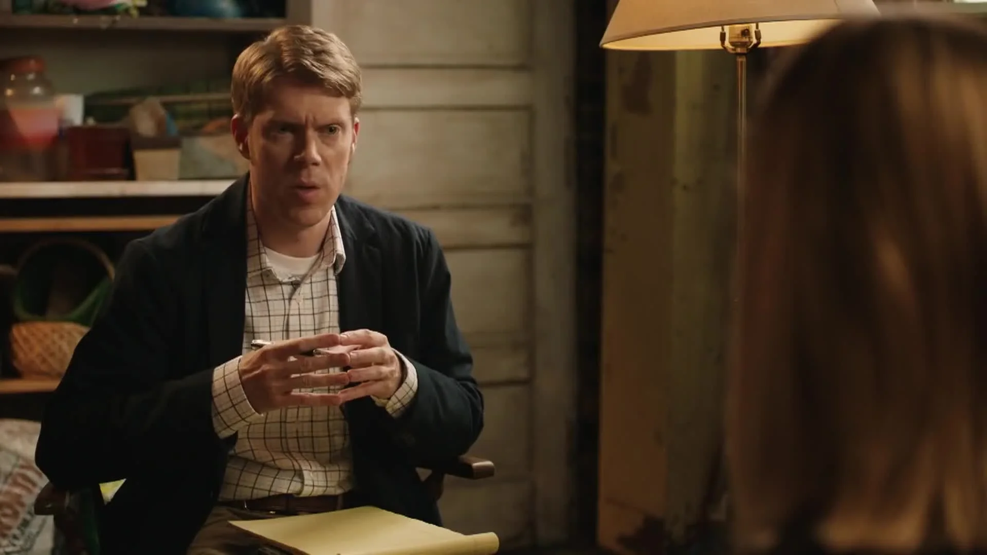 Close-up of Tim Baltz holding a pen and yellow notepad with a focused expression during a therapy session in Shrink.