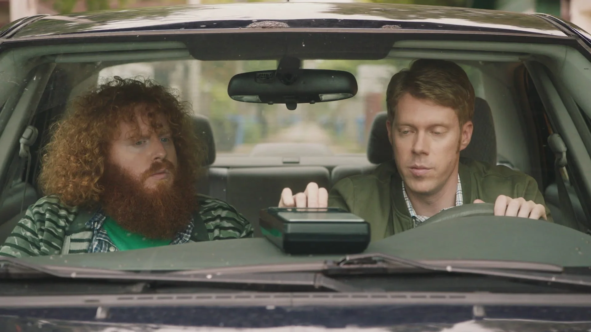 Tim Baltz sitting in the driver's seat of a car next to a bearded patient in Shrink.