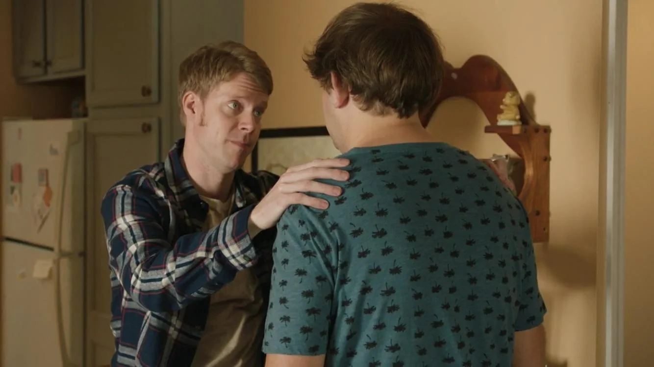 Tim Baltz placing a reassuring hand on a young man's shoulder inside a house in Shrink.