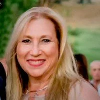 Portrait of a smiling woman with long blonde hair outdoors.