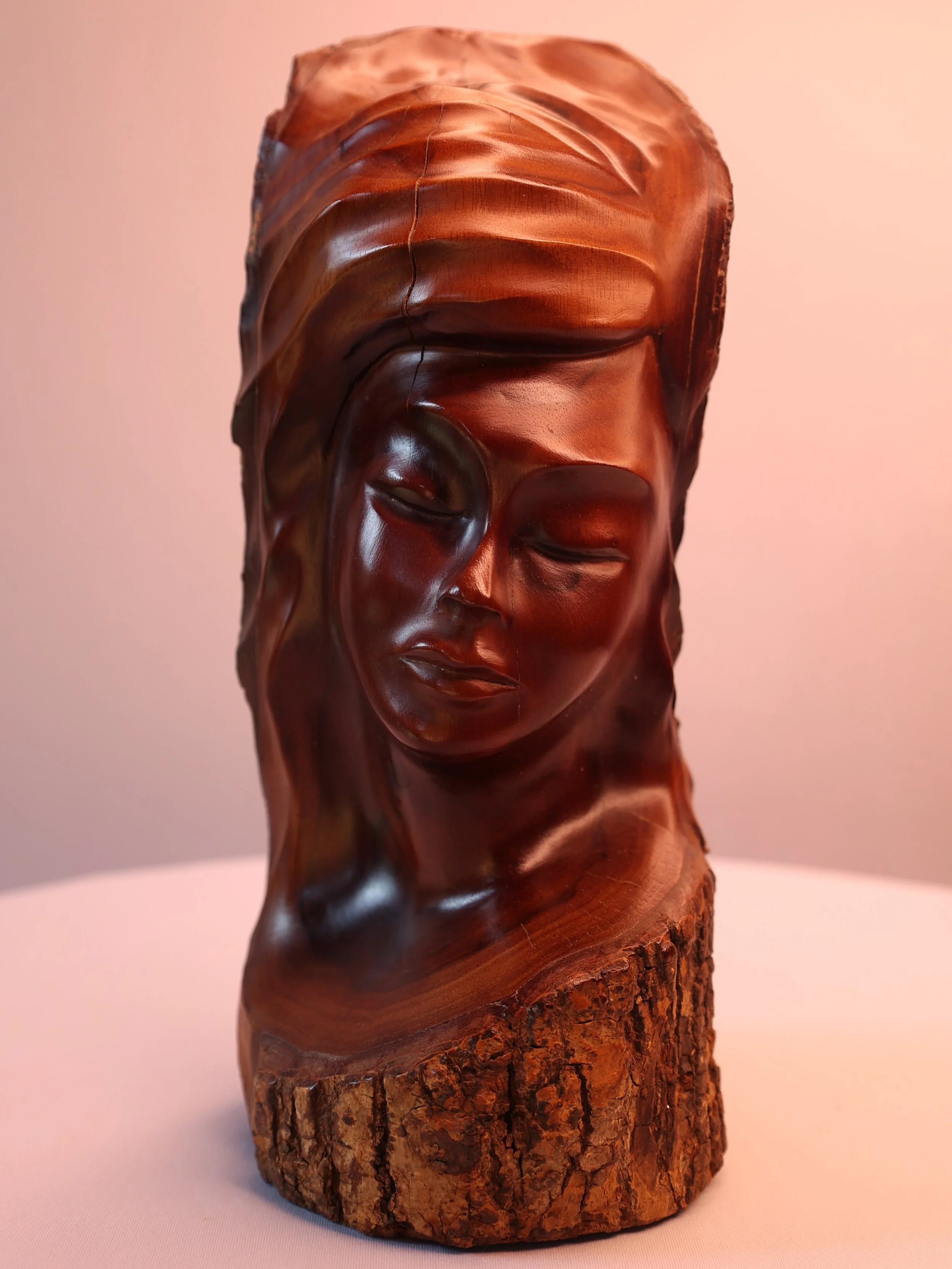 Exquisite and rare, this late 20th-century carved bust captures the timeless elegance of the female form, masterfully rendered in indigenous Hawaiian Milo wood.
Hand-carved and signed on the base by artist Brandon Blair, this piece highlights the nat