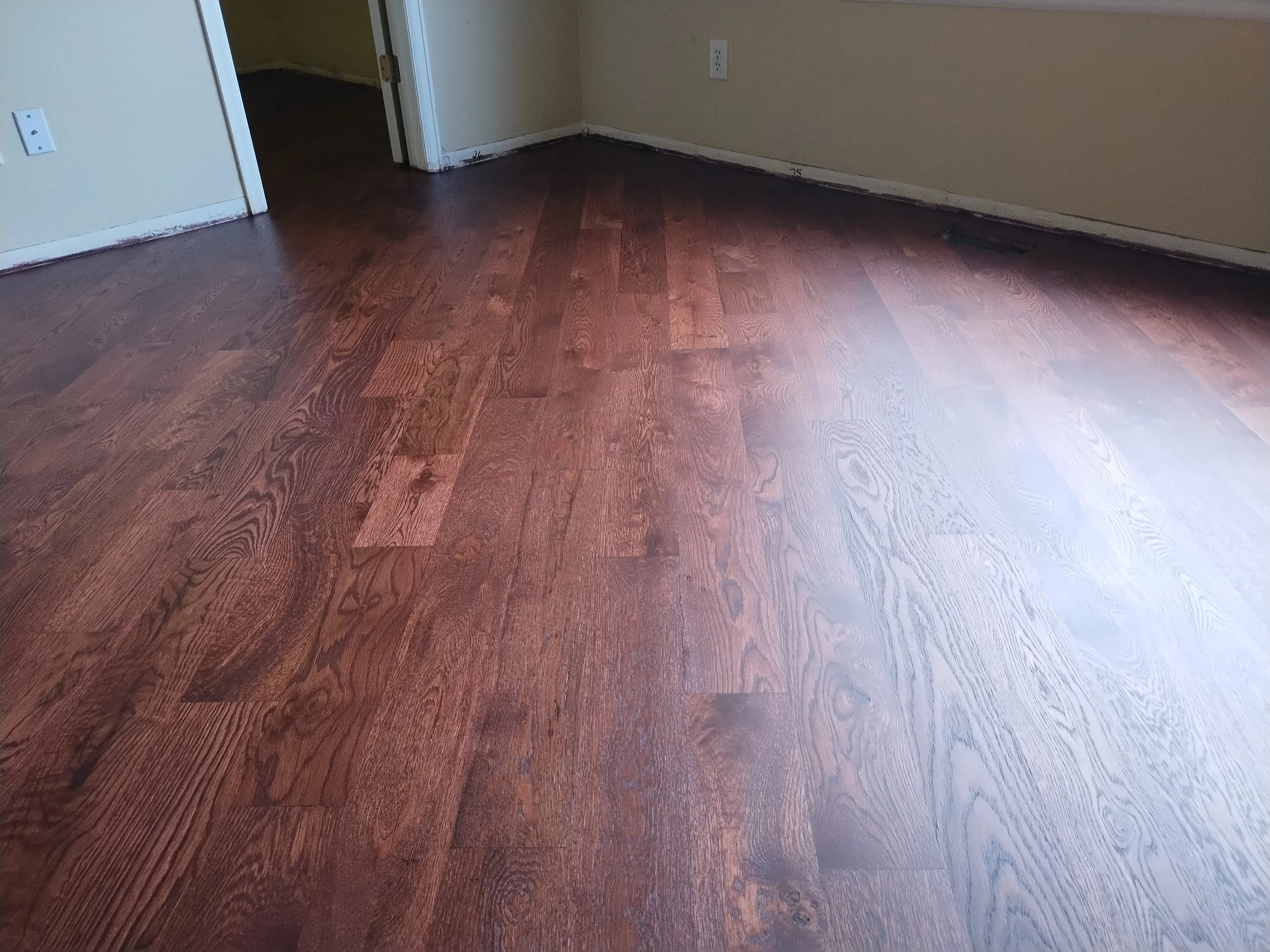 Room with hardwood floors, a doorway, beige walls, and electrical outlets.