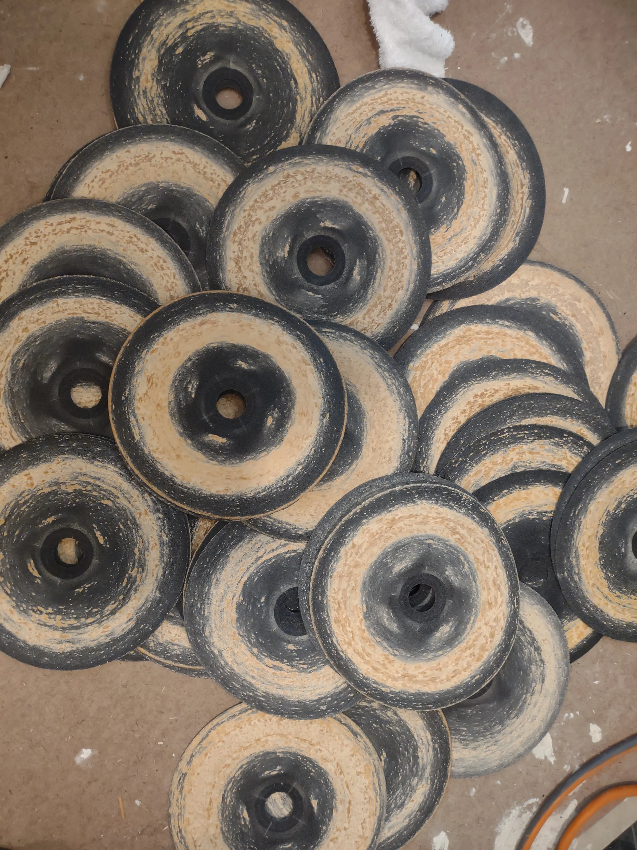 Several black and beige skateboarding wheels with dirt and wear, arranged on a dusty concrete floor.