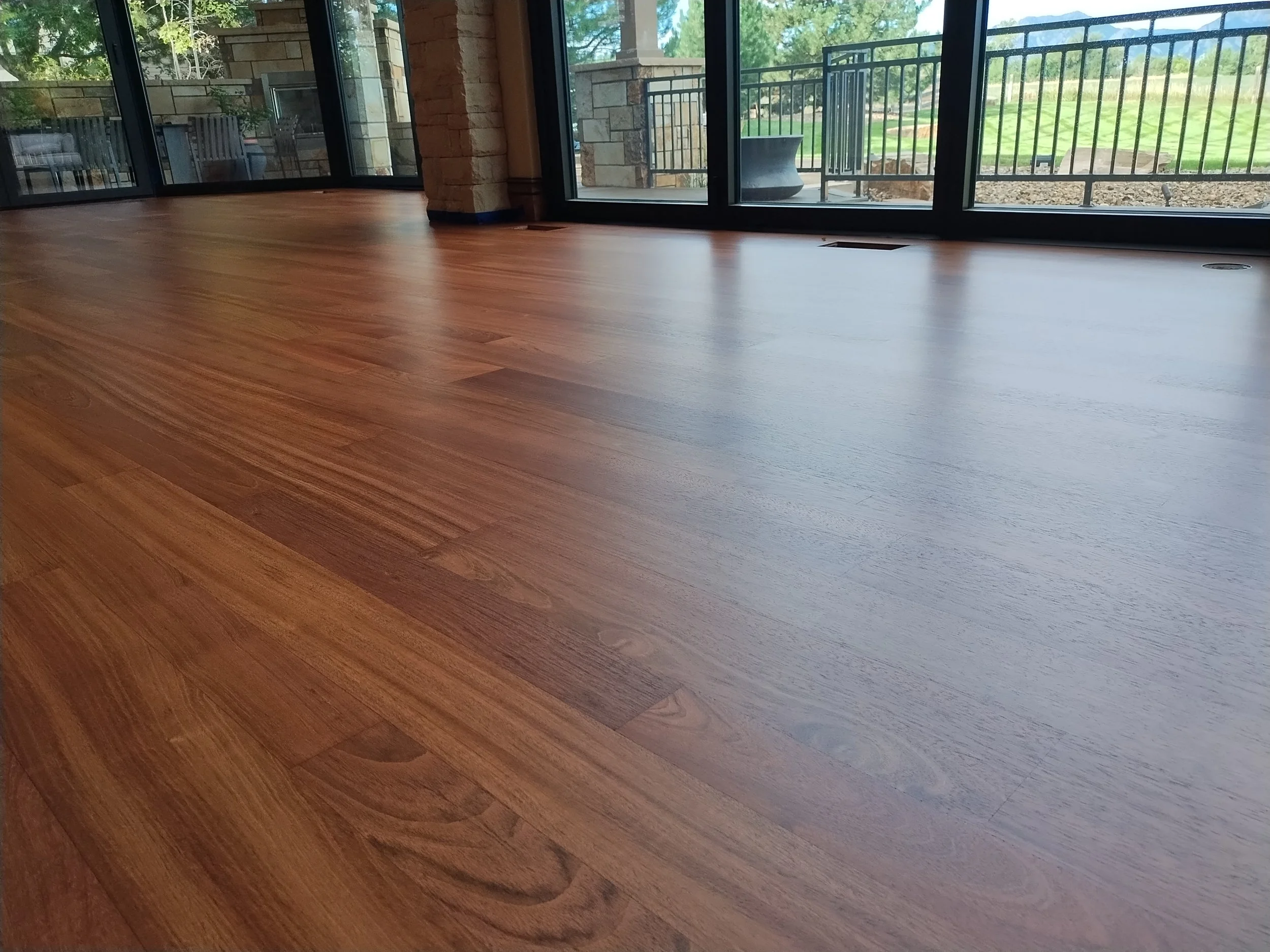 Interior view of a room with a hardwood floor, large glass sliding doors, and a view of a patio and green yard outside.