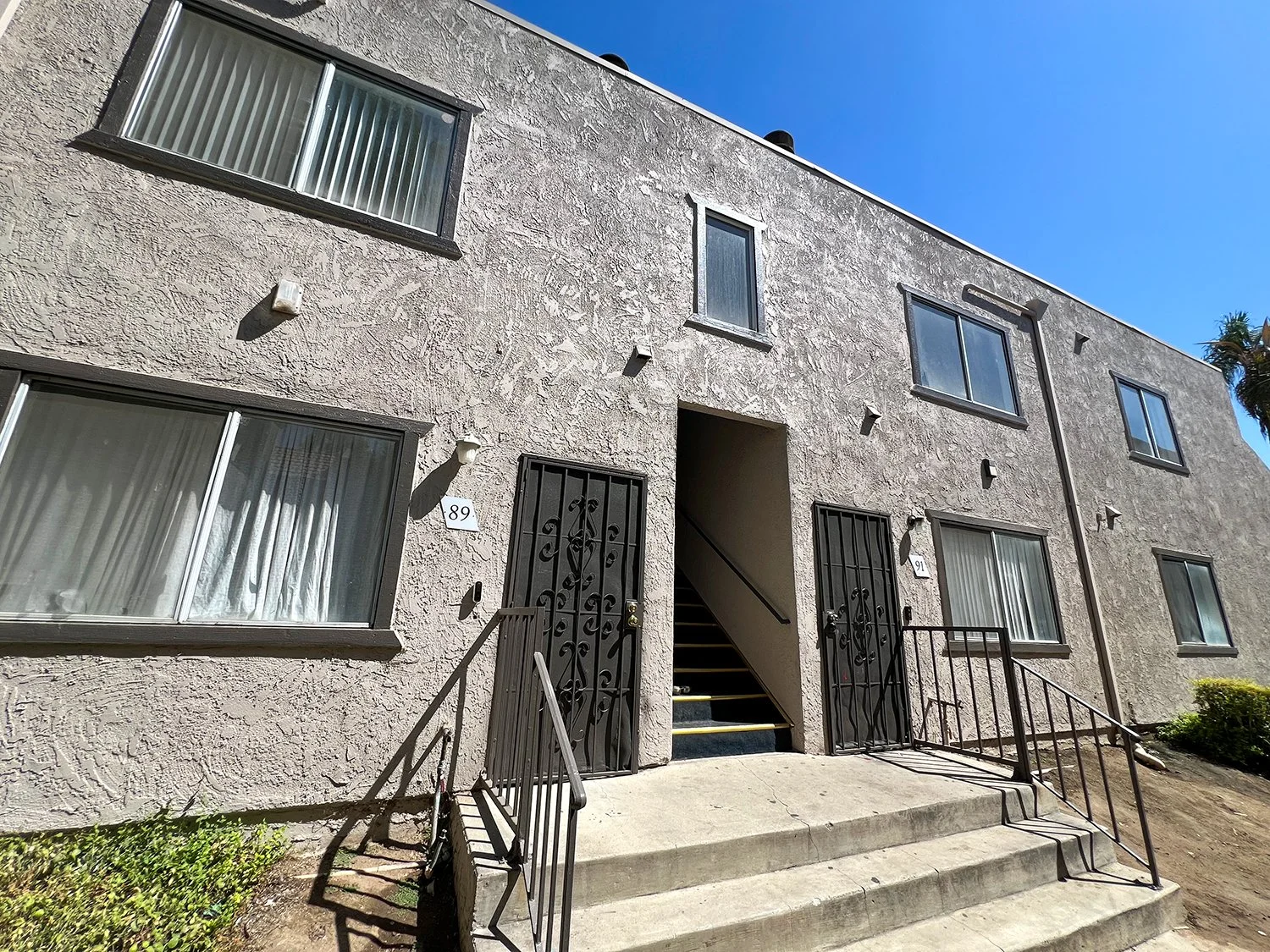 Cozy exterior of Highland Club Apartments with surrounded by large shade trees and lush grass.