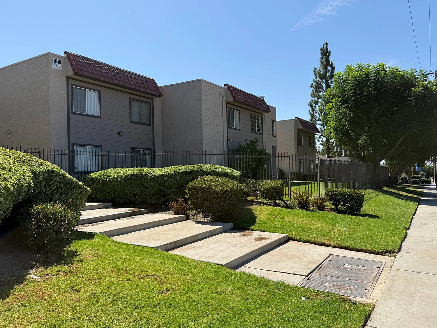 Cozy exterior of Highland Club Apartments with gated entry and grass lined steps leading to pedestrian entry gate. 