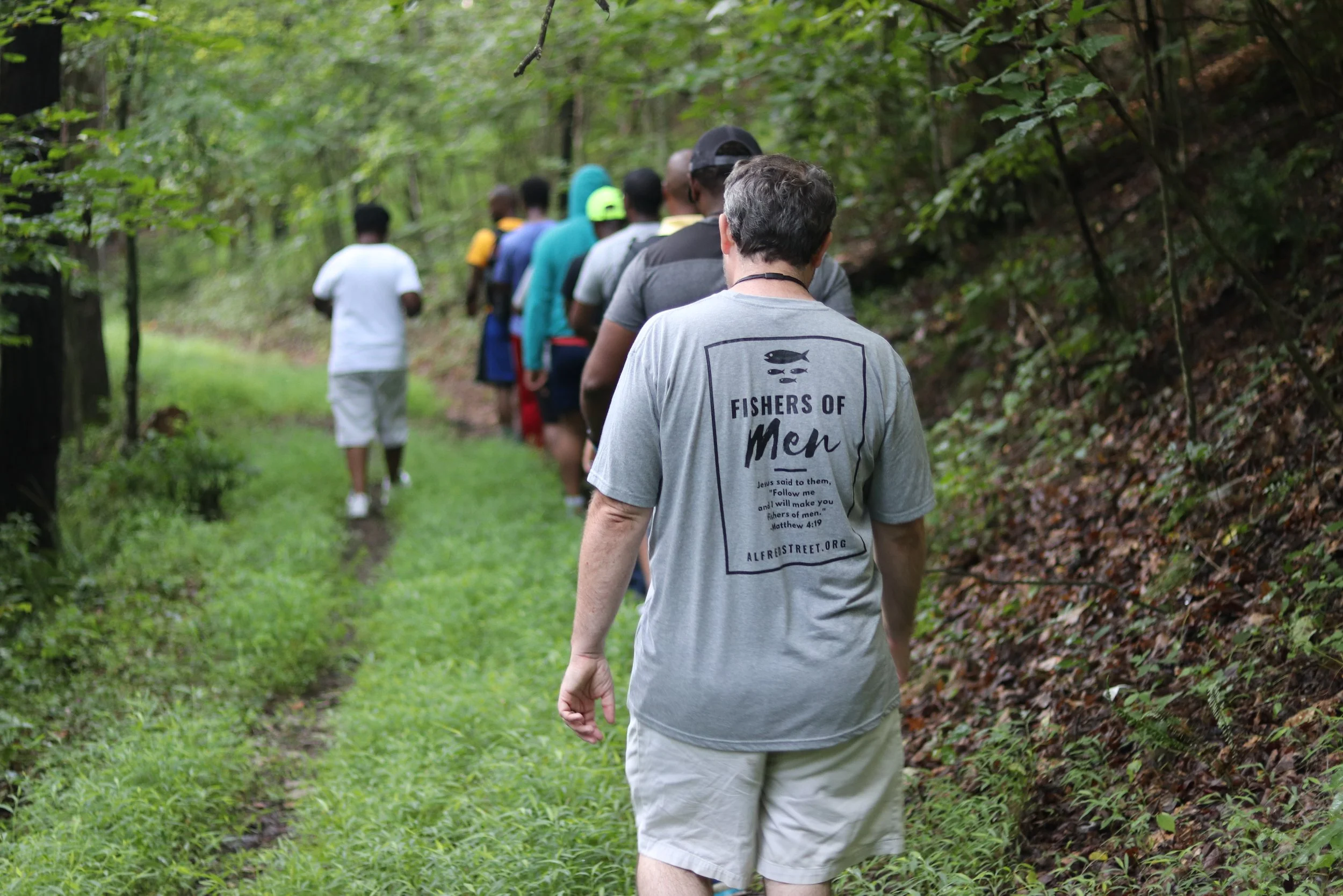 Group of hikers walking together along a dirt path through the woods.