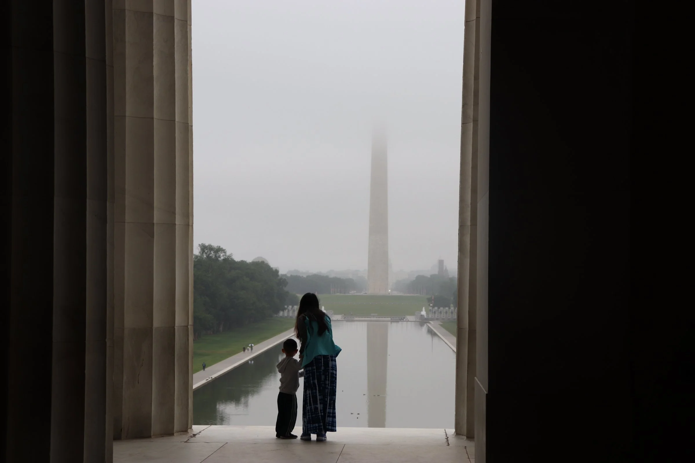 Mother and young son standing together at the Lincoln Memorial in Washington, DC at sunrise