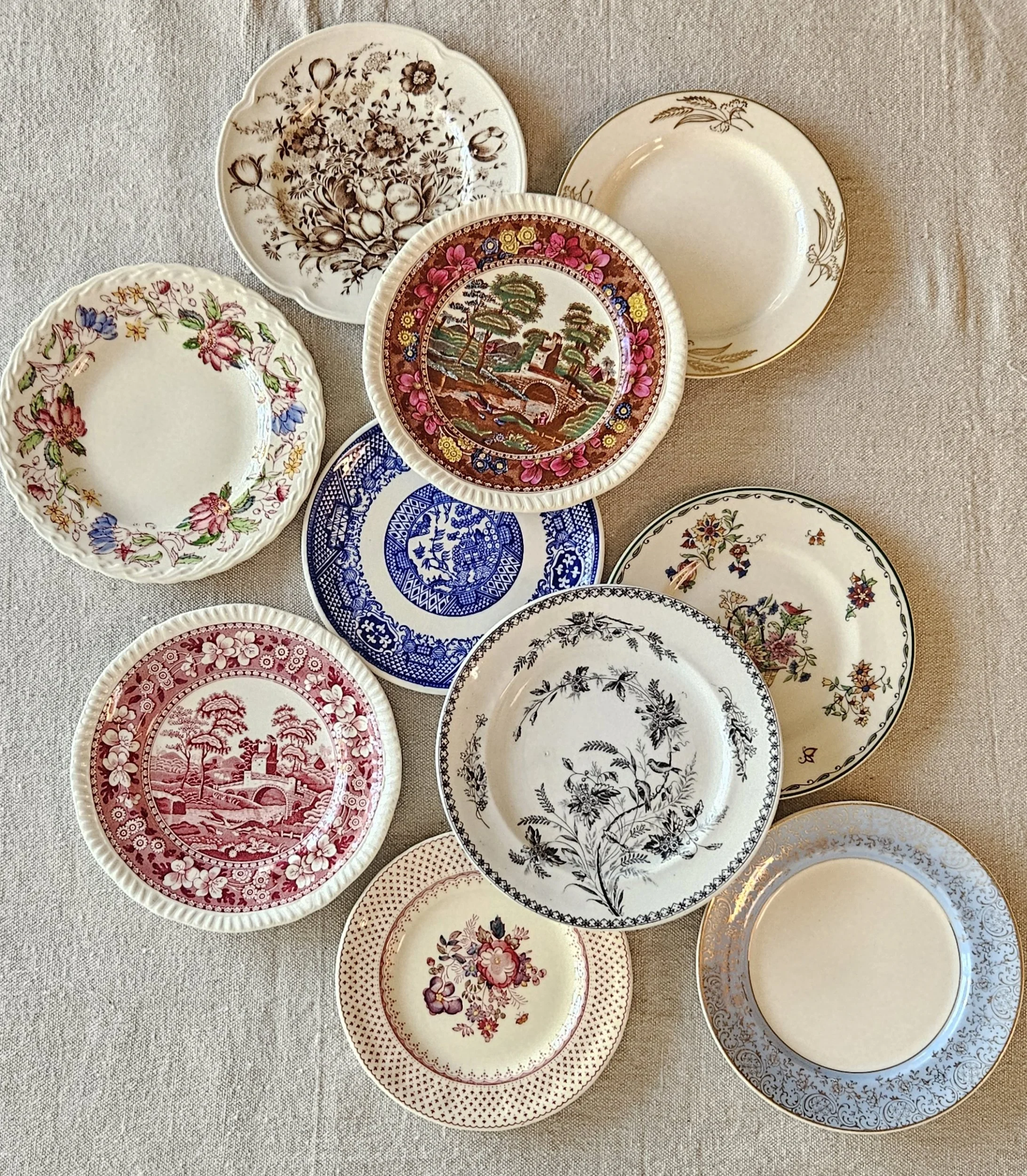 Collection of decorative plates with various floral and scenic patterns arranged on a table.