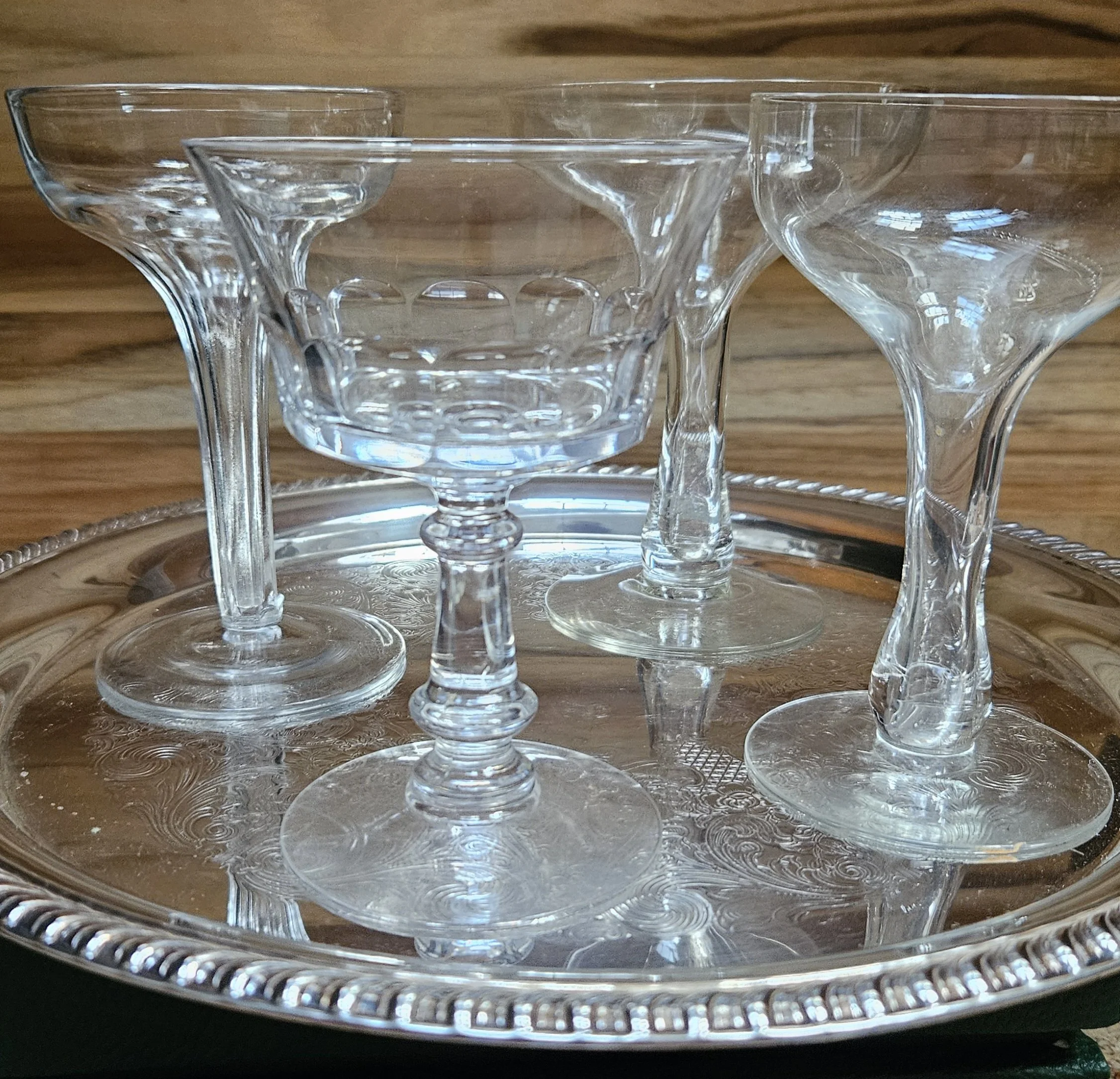 Set of clear glass dessert cups placed on a silver tray on a wooden surface.