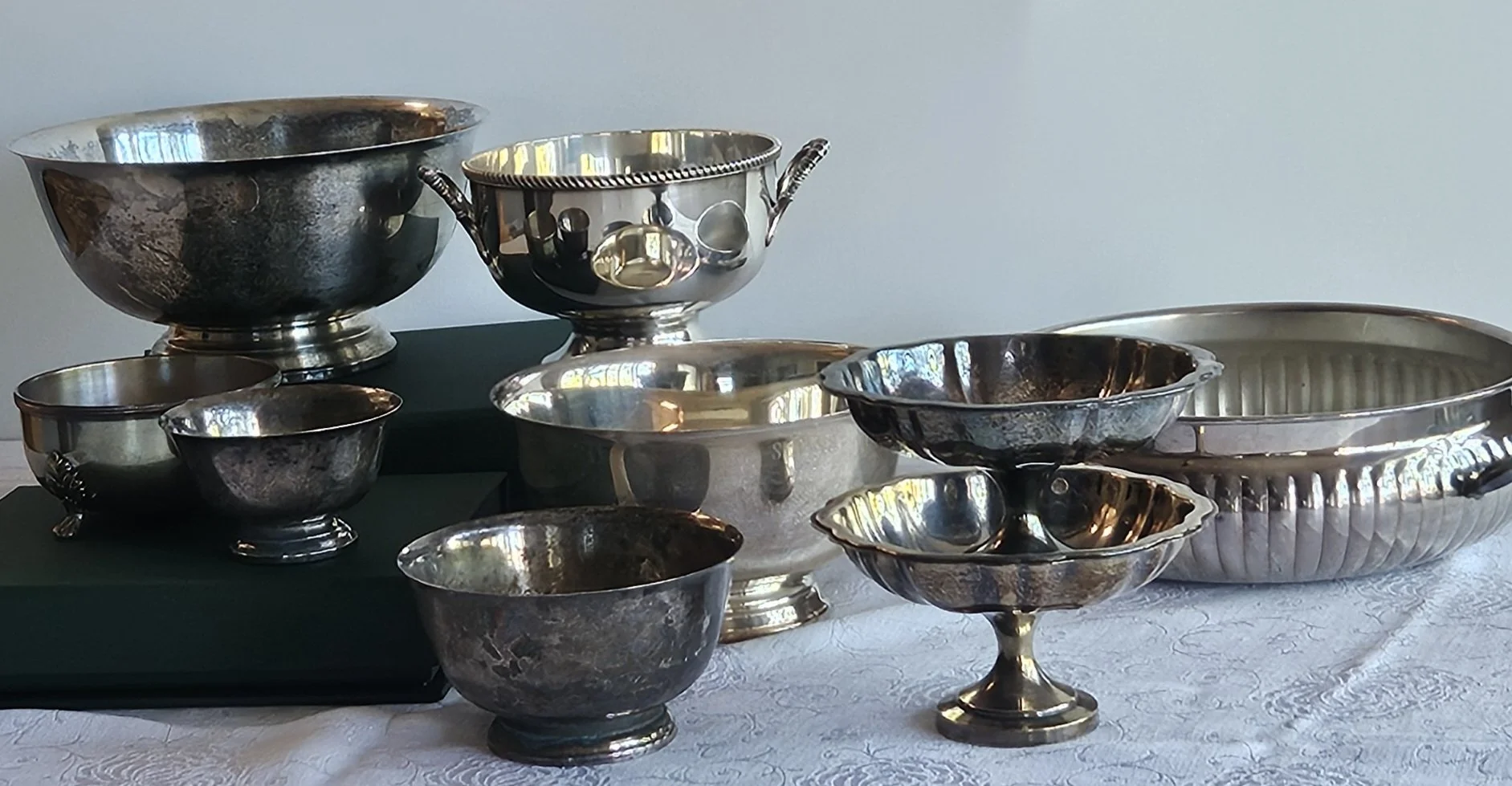Collection of shiny silver and metal bowls of various sizes and designs displayed on a table.