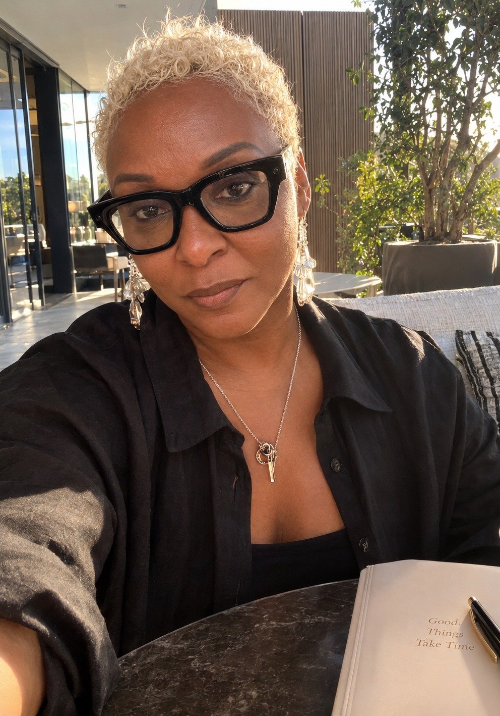 LeShanda Davis, founder of Sacred & Soft, seated outdoors with her journal