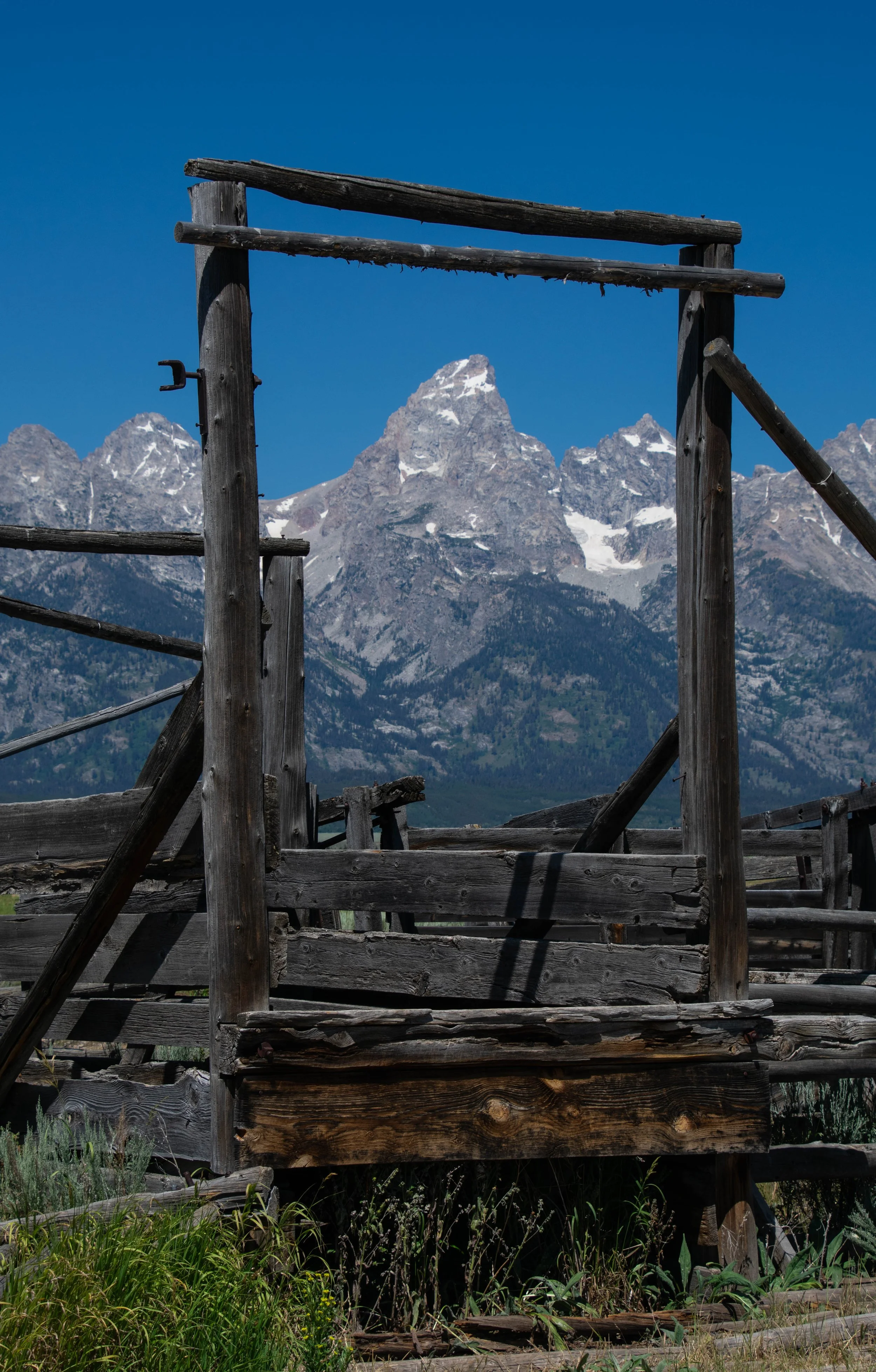 Old wooden structure with mountains in the background under a clear blue sky.