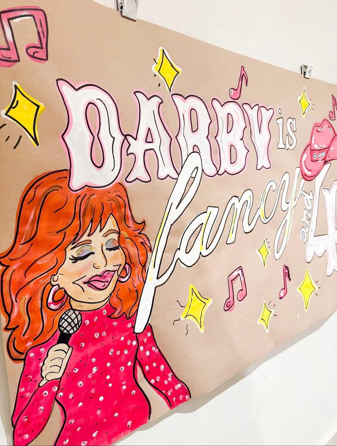 Colorful drawing of a woman with long red hair holding a microphone, with the text 'Every girl is a Rockstar' and various musical notes and stars on a tan background.