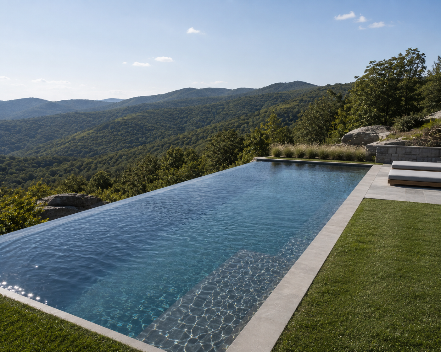 Luxury infinity pool overlooking a mountainous landscape with green trees on a sunny day