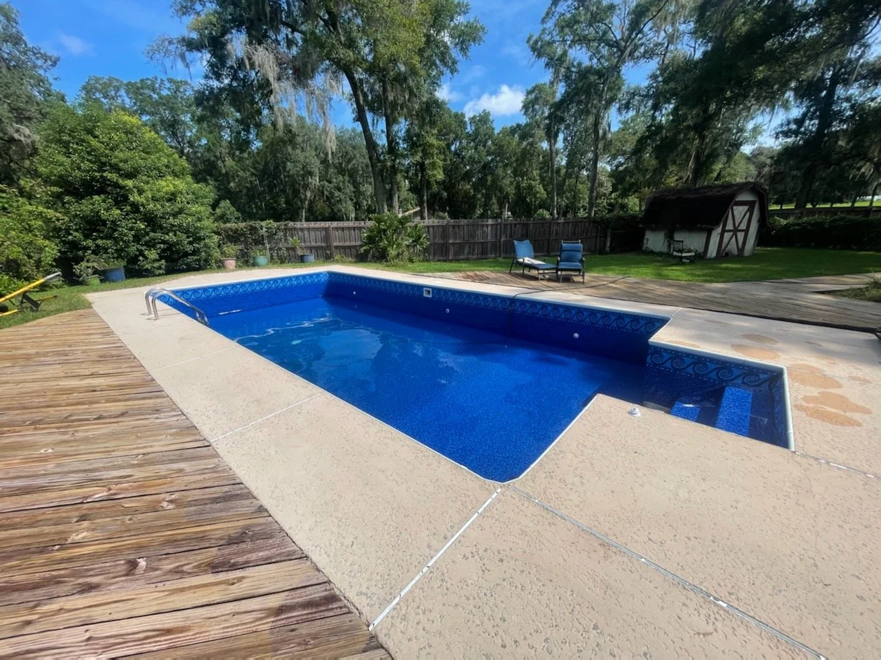 Completed inground pool liner installation with blue liner and metal ladder.