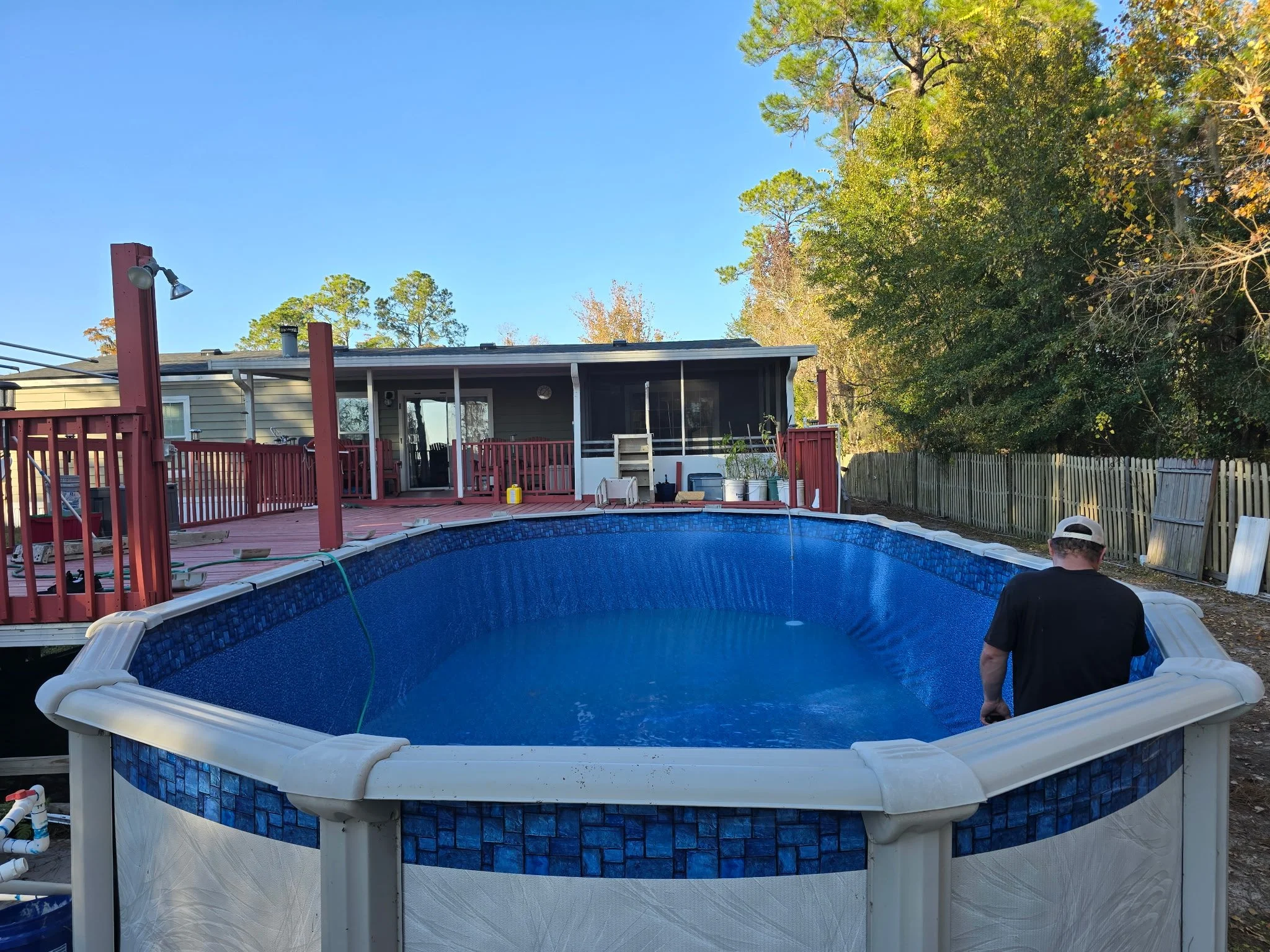 Above-ground swimming pool installation with blue liner and surrounding deck.
