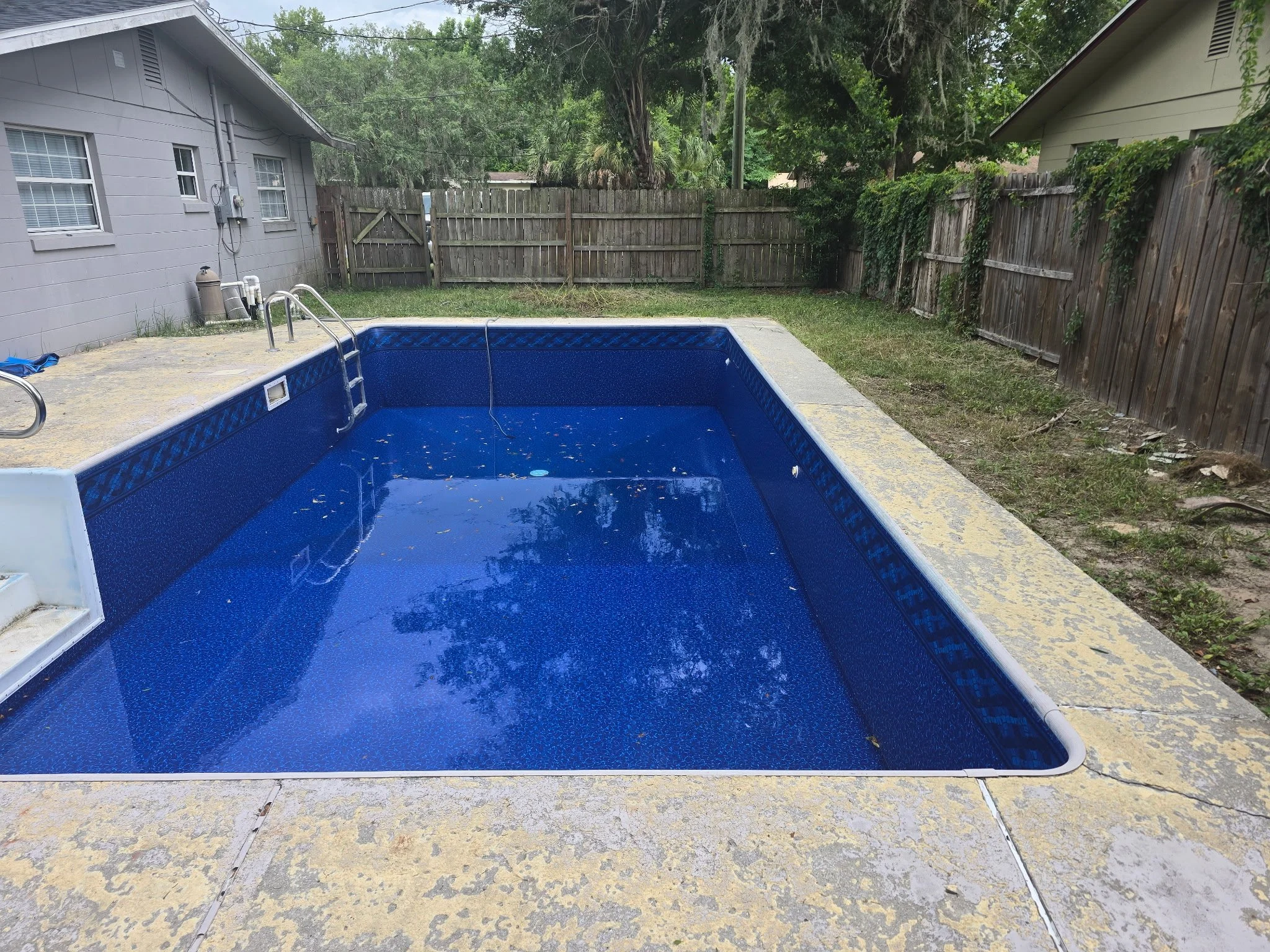 Completed inground liner replacement with blue liner and concrete deck.