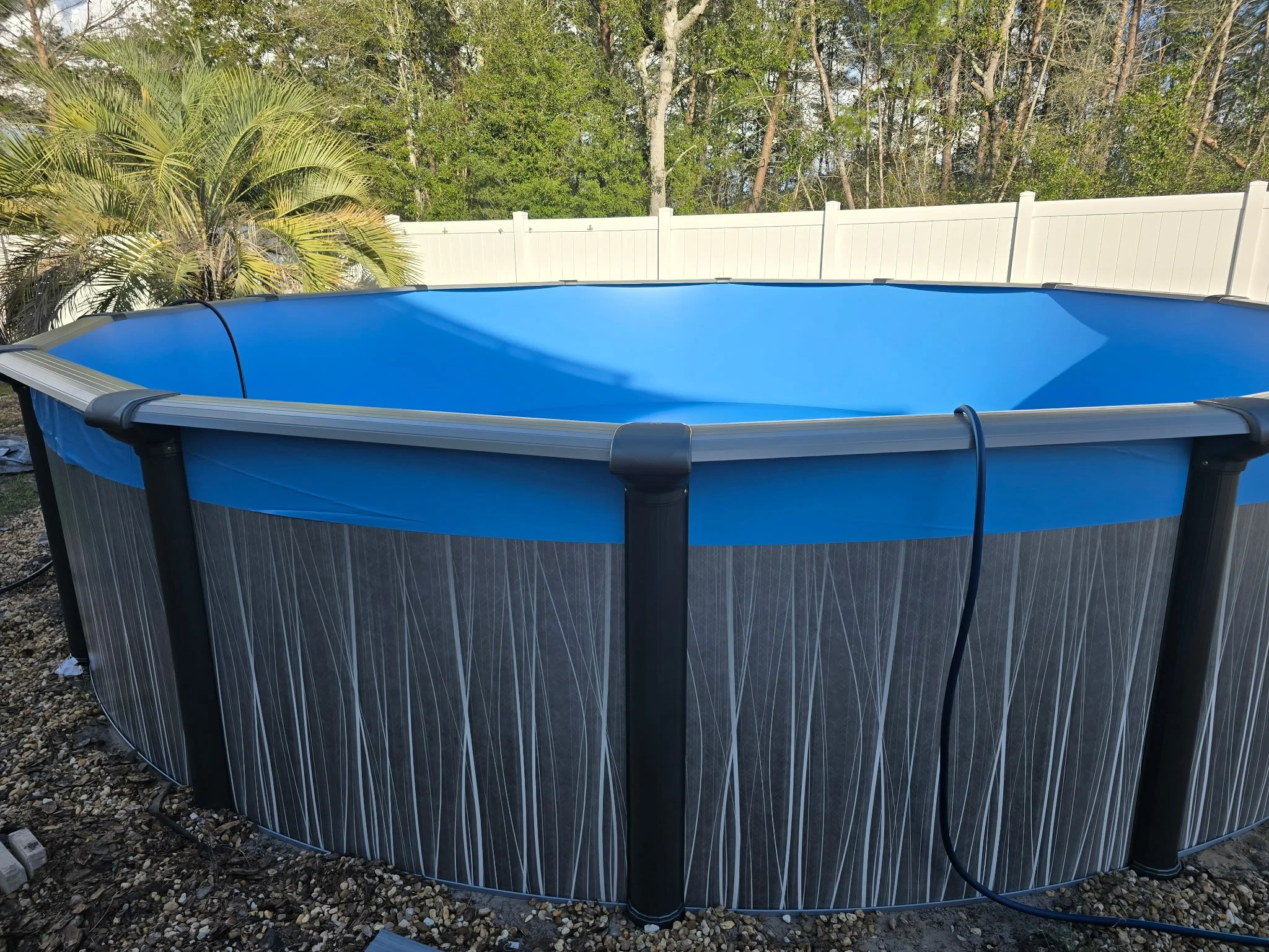 Completed above-ground swimming pool installation with blue liner and black exterior.