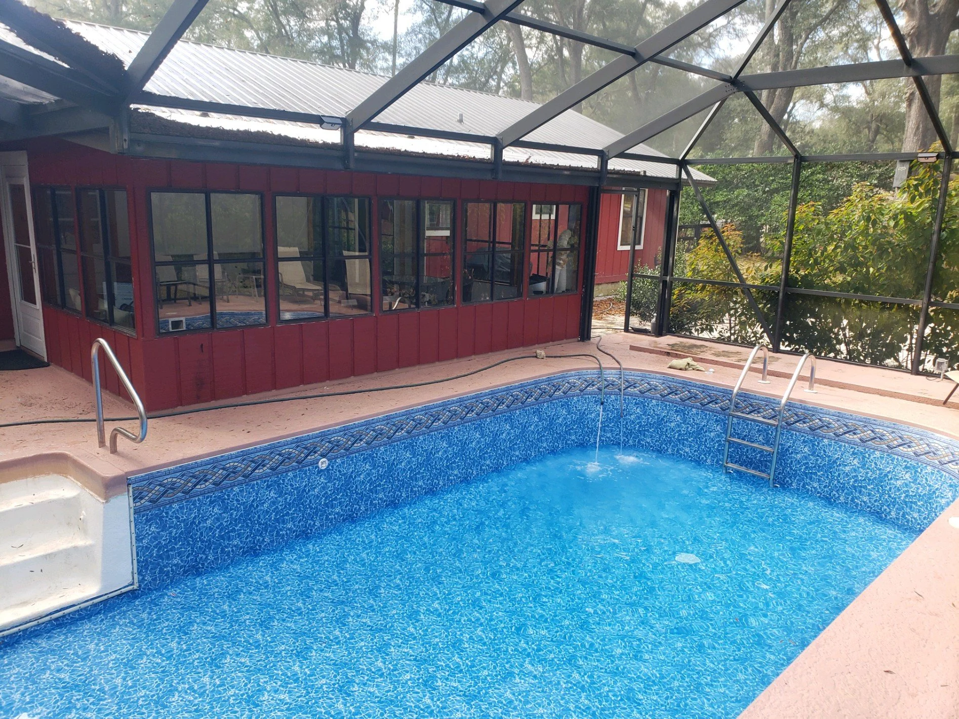 Completed inground pool liner replacement with blue mosaic liner and metal handrails. 