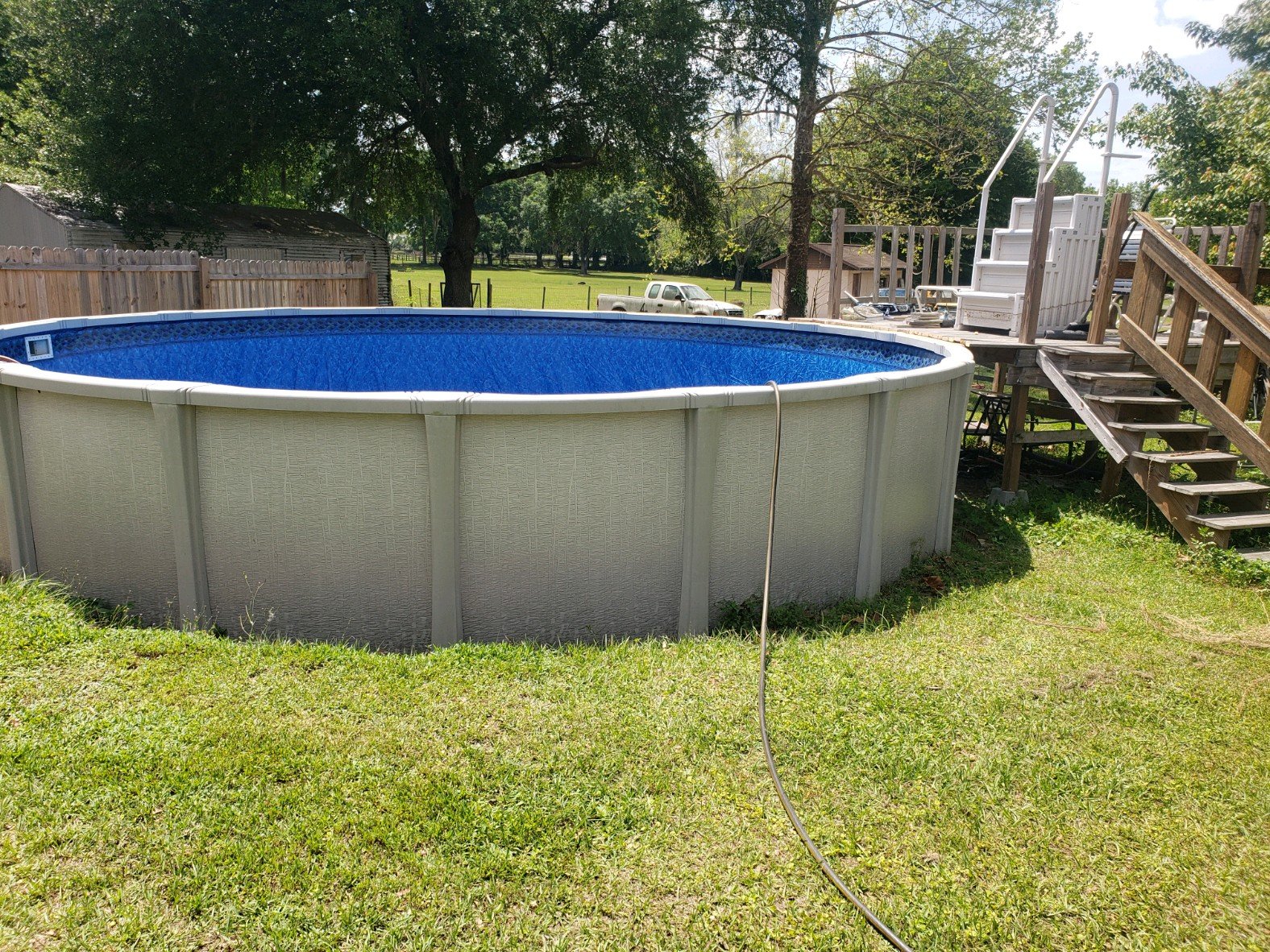 Completed above-ground swimming pool installation with blue liner and white exterior.