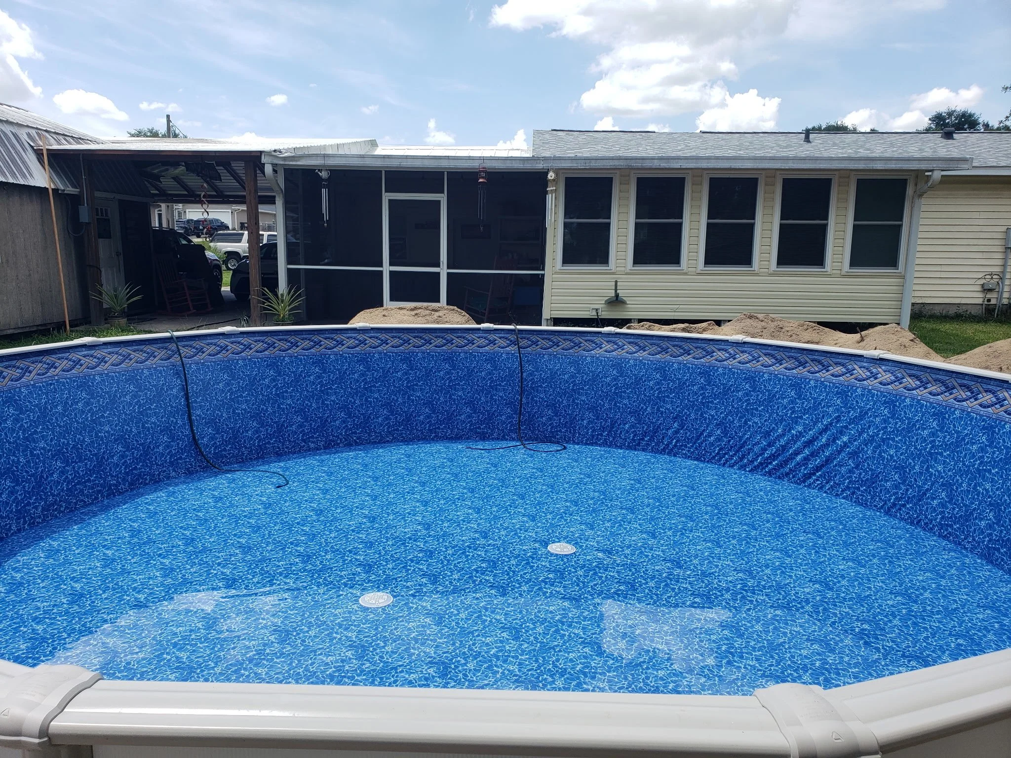 Above-ground swimming pool installation with blue liner while filling with water.