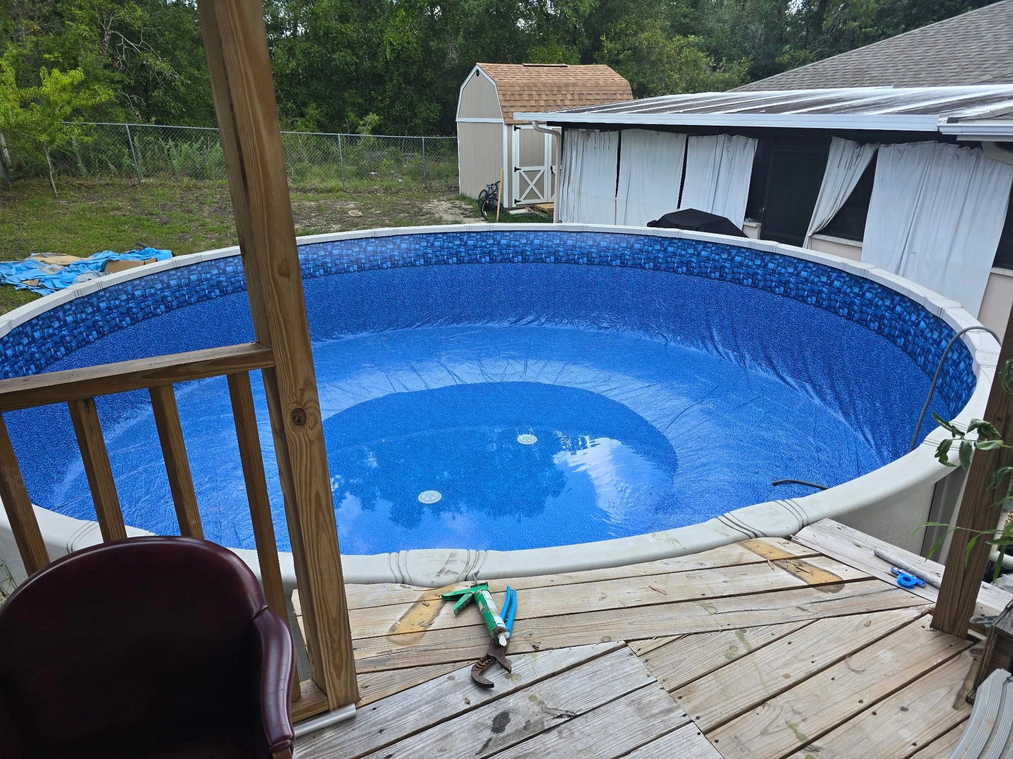 Above-ground swimming pool with blue liner and surrounding wooden deck.