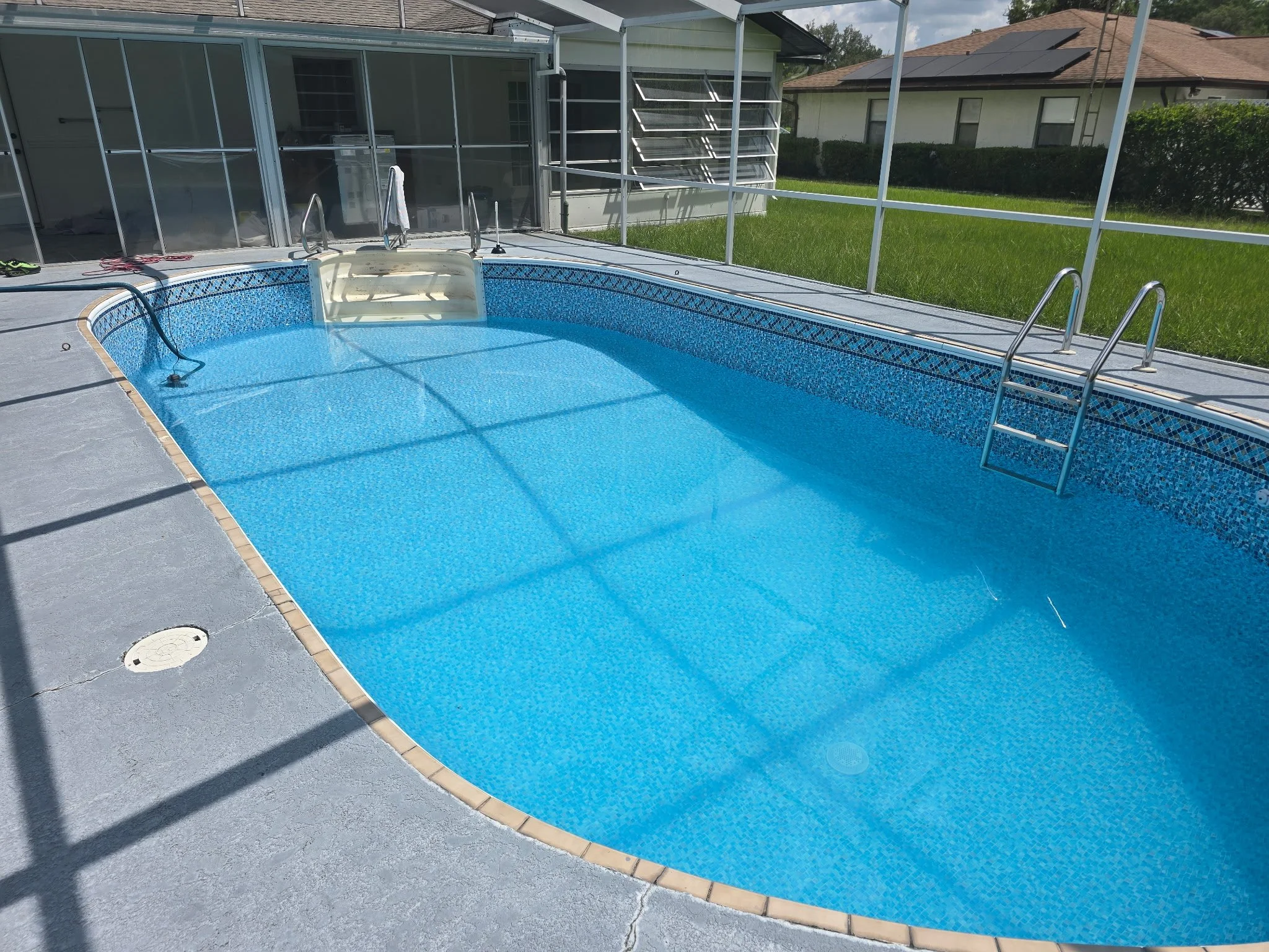 Inground swimming pool with new blue liner, steps and screened enclosure.