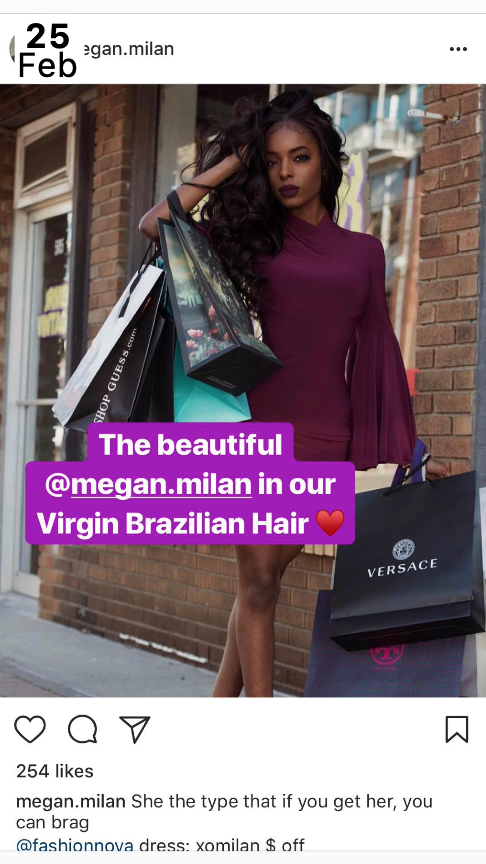 A woman with long dark curly hair wearing a purple dress with bell sleeves, standing outside a brick building, holding shopping bags from Versace and Guess.